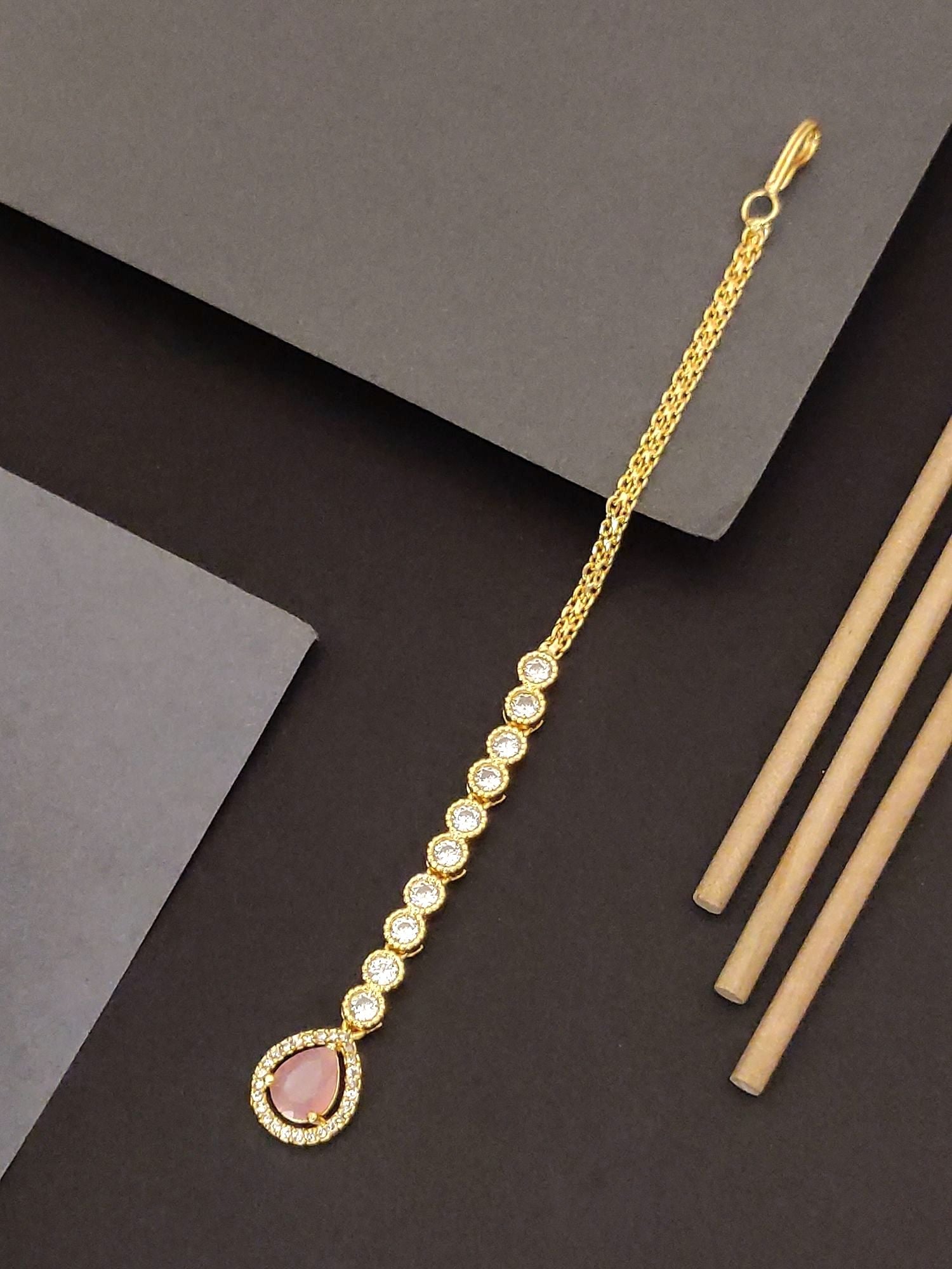 Gold-plated maangtikka with pink stone and sparkling embellishments for traditional elegance