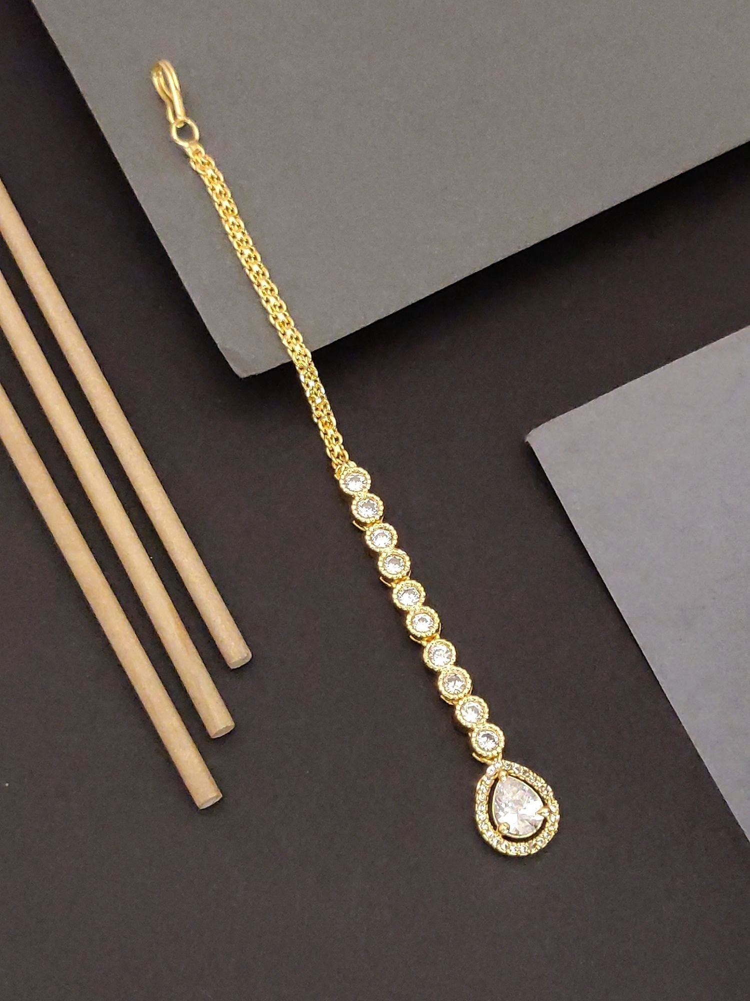 Elegant gold-plated maangtikka with a teardrop pendant and sparkling stones for traditional occasions