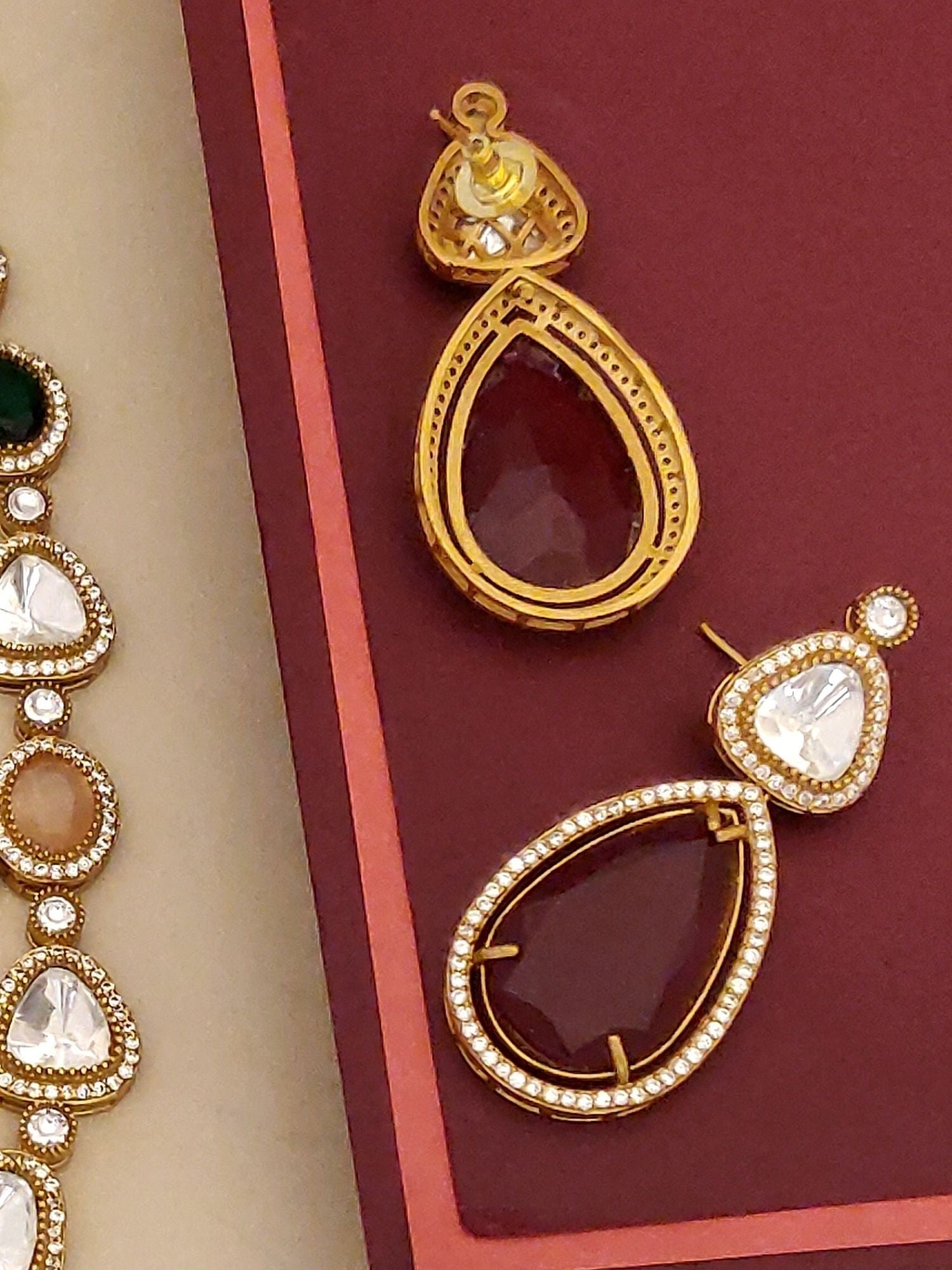 Abdesignsjewellery gold plated polki necklace set with teardrop polki stones and matching earrings on burgundy background