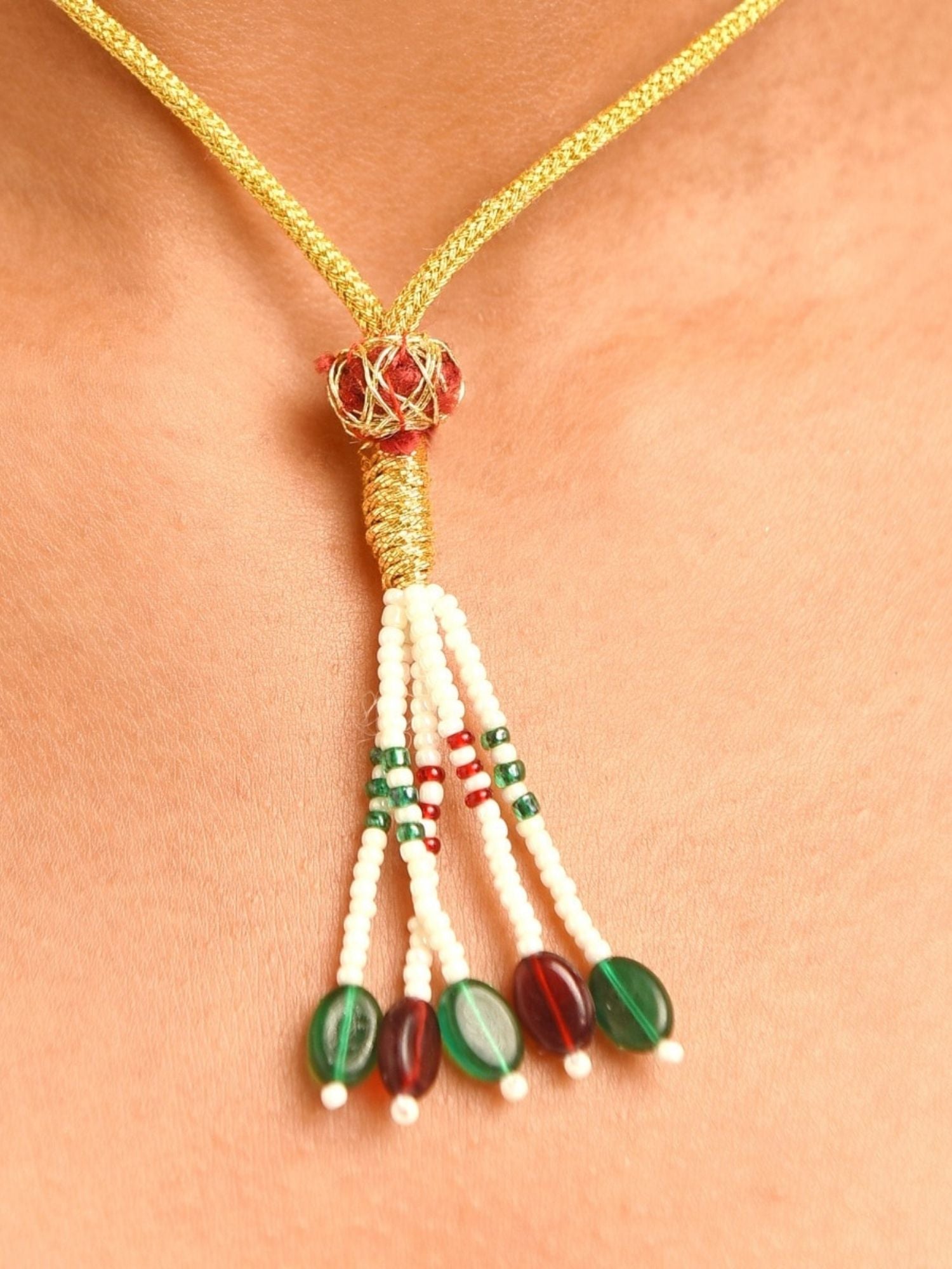 Gold plated polki necklace set featuring braided gold cord with beaded tassel of white green and red beads