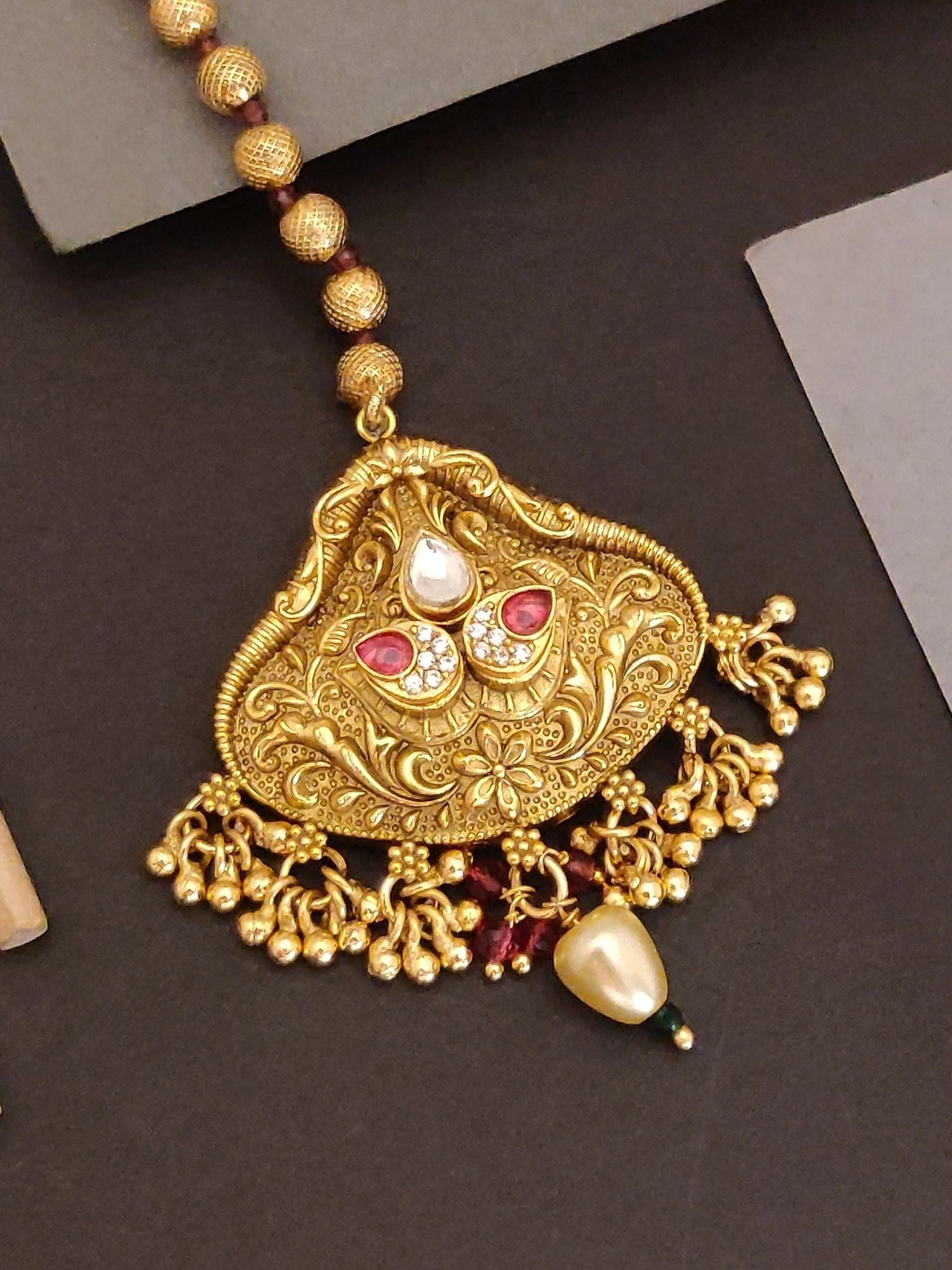 Abdesigns Jewellery Maangtikka Elegant Gold-Tone Design with intricate floral patterns and red and white stones