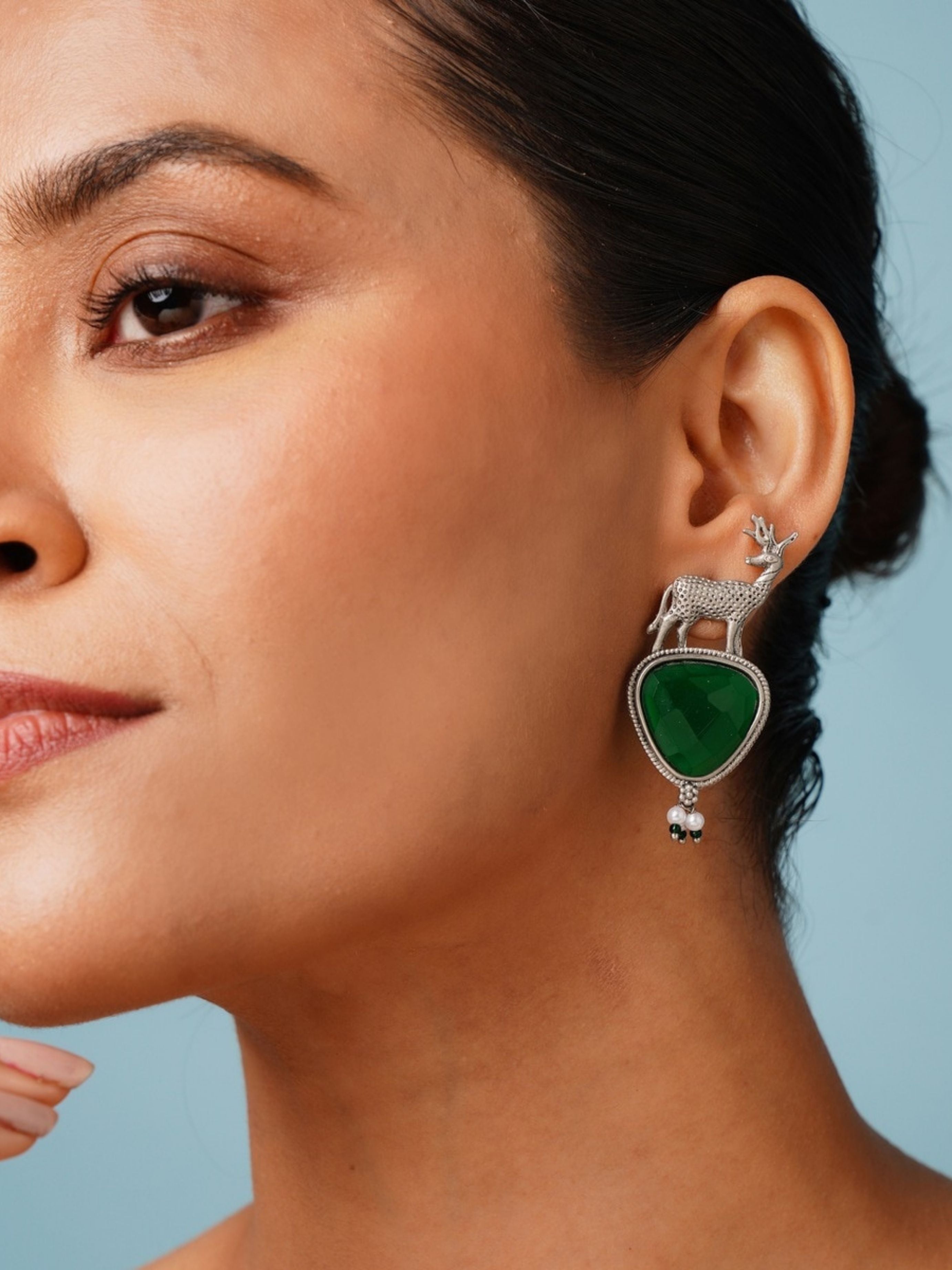 Abdesigns Jewellery Silver Deer Green Stone Earrings worn on woman's ear with detailed deer design