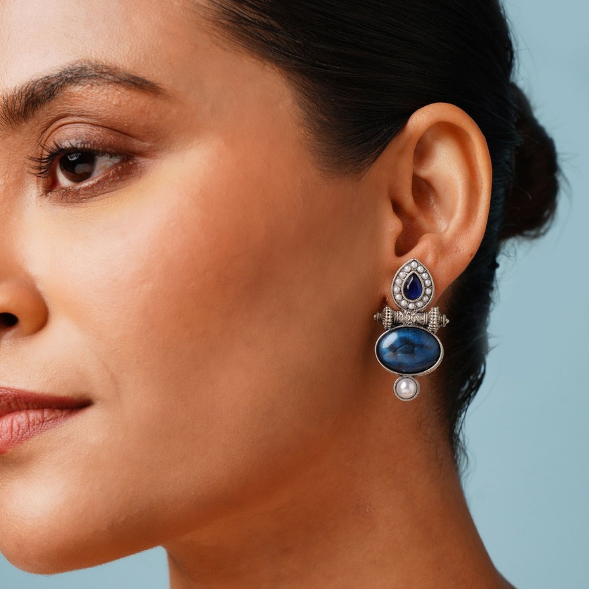 Abdesigns Jewellery Silver Plated Blue Stone Pearl Earrings worn by woman with blue background
