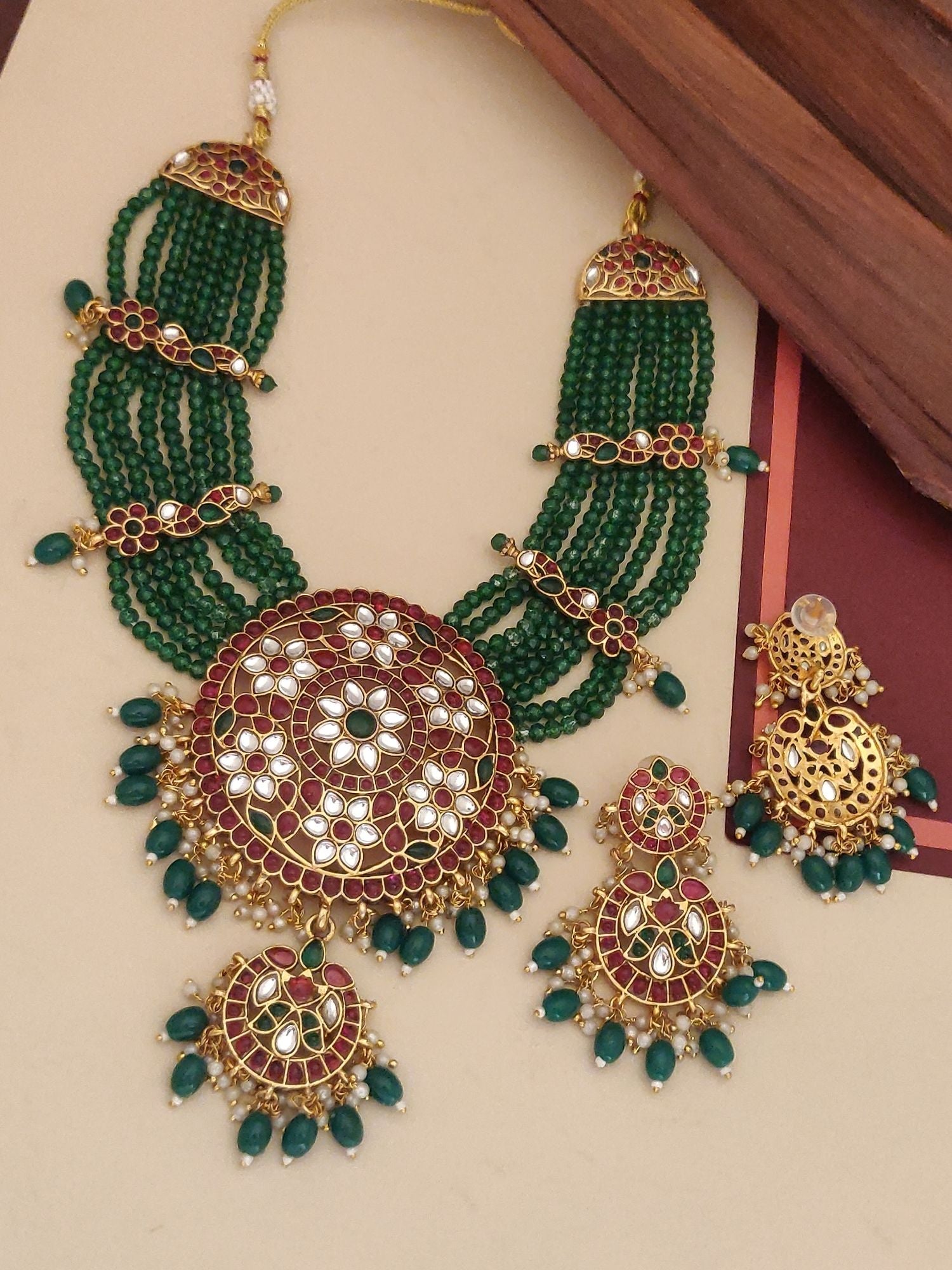kundan green beads pendant set featuring multi strand green bead necklace gold and red floral pendant with matching earrings