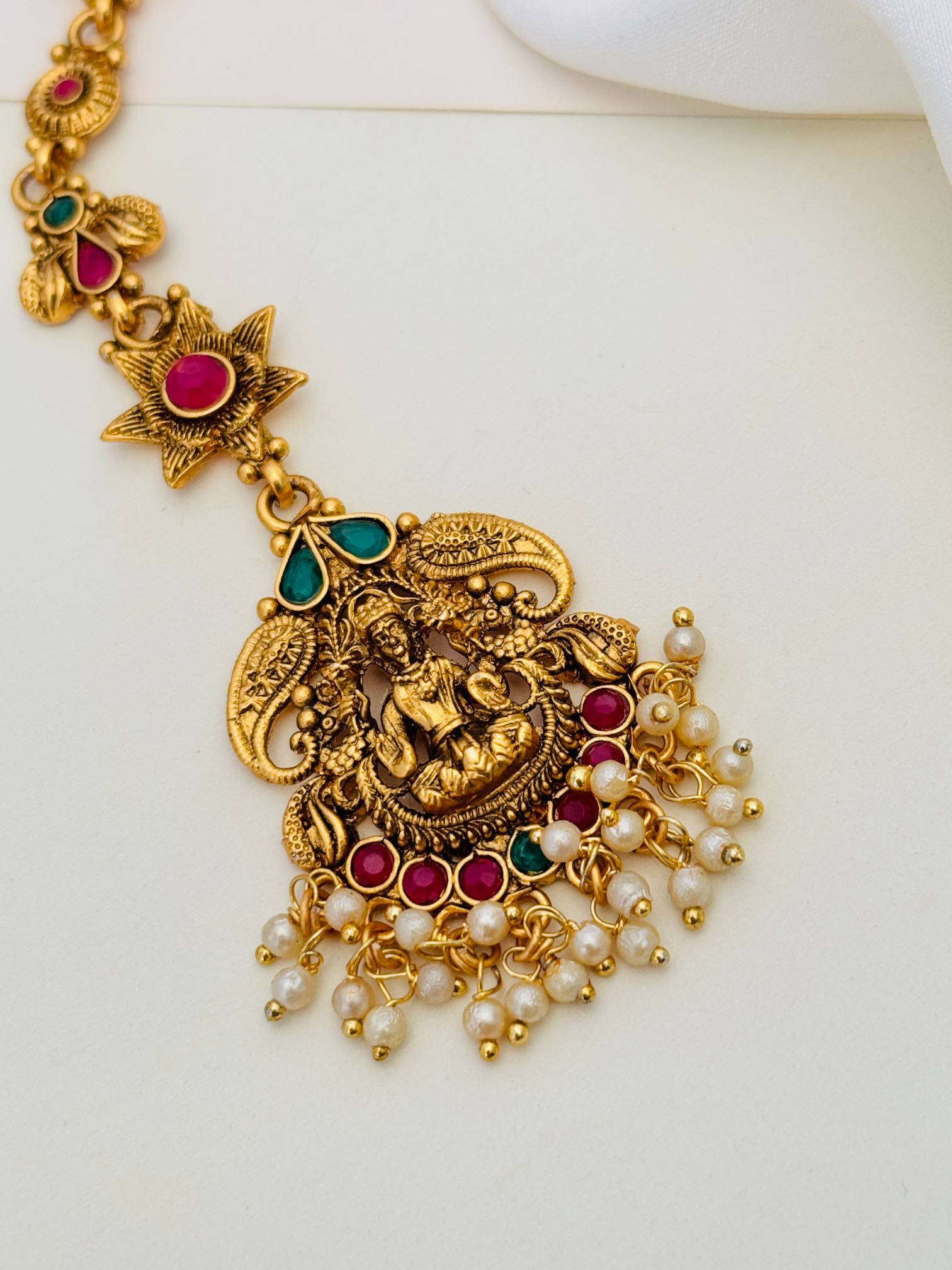 Matt Gold Plated Goddess Laxmi SouthIndian Maangtikka with intricate design pearls and red green stones by Abdesignsjewellery