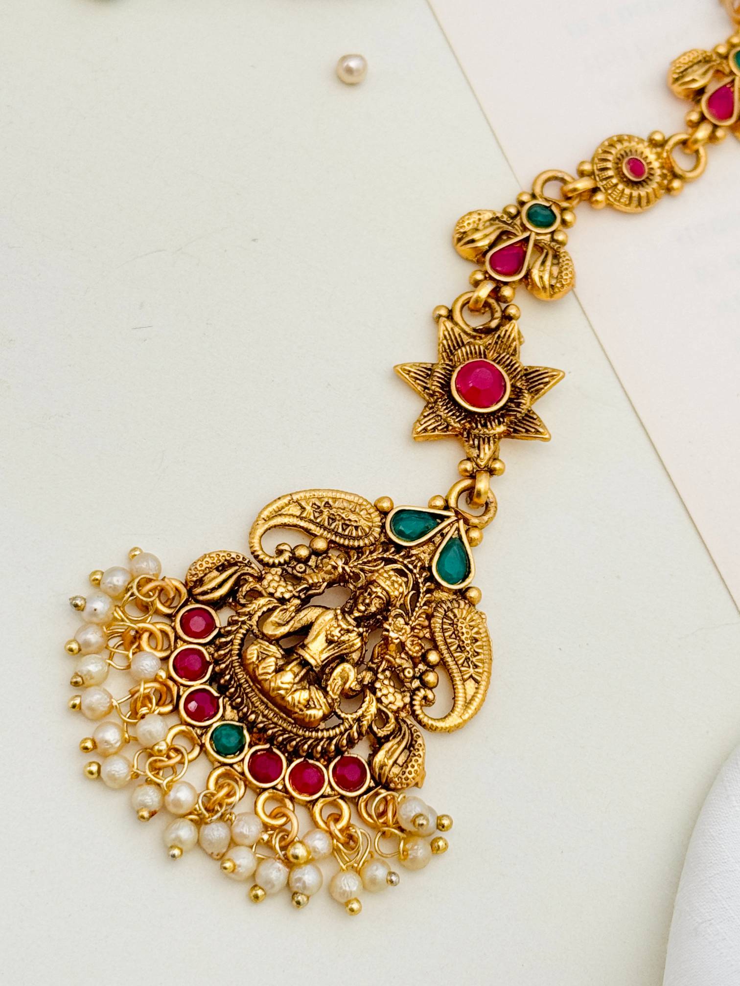 Matt Gold Plated Goddess Laxmi SouthIndian Maangtikka with red and green stones and pearl detailing