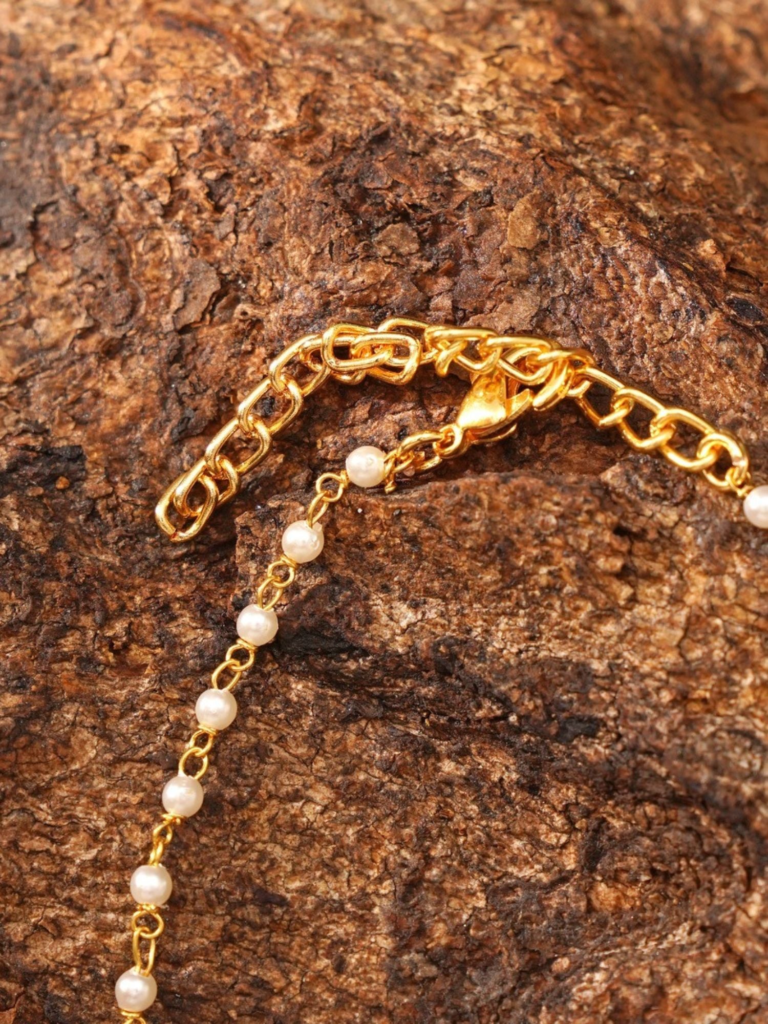 minimal gold plated hand pocha bracelet with delicate pearl chain and lobster clasp on textured wood background