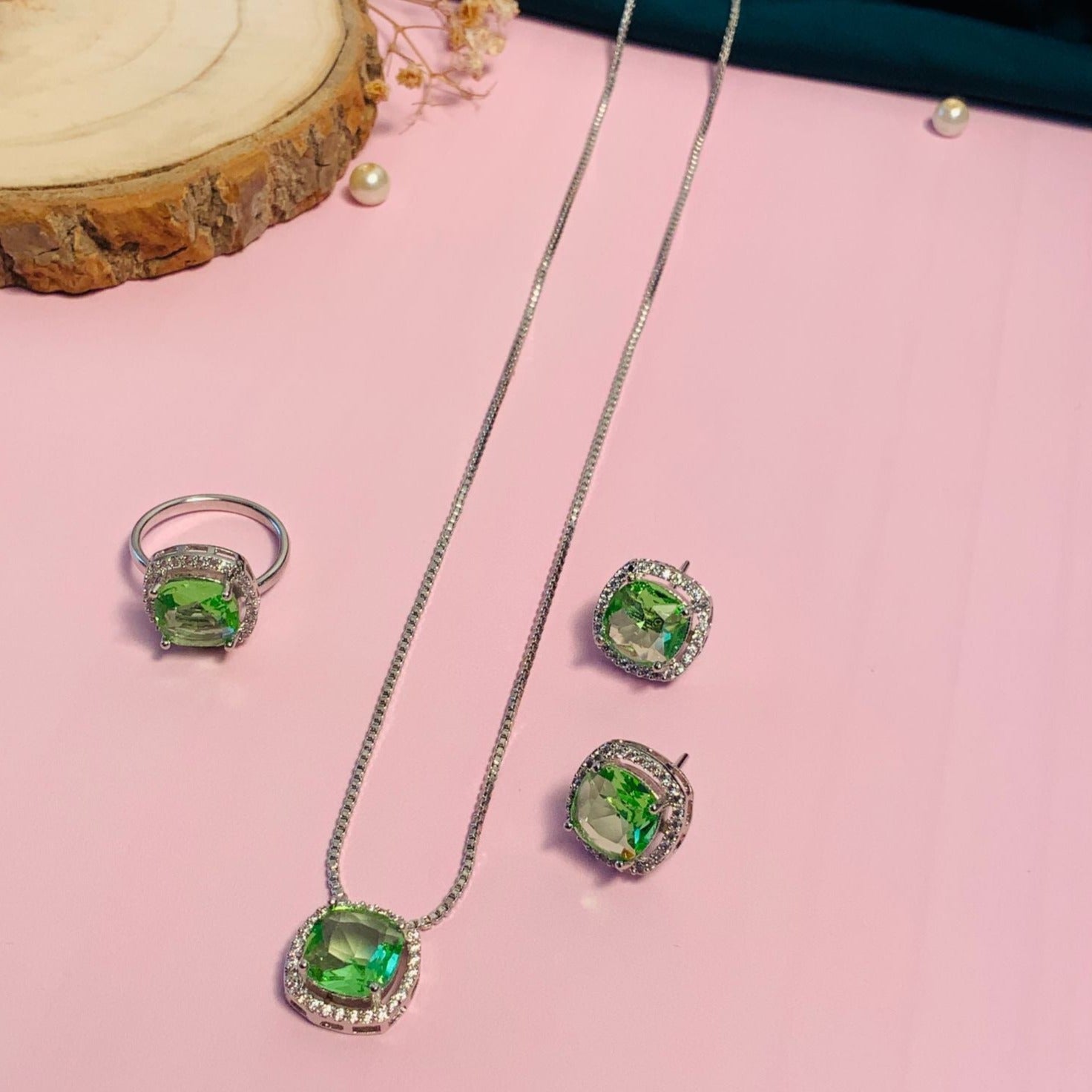 Precious Silver Plated Cz Pendant Chain Combo with green stone ring, earrings, and necklace on pink background