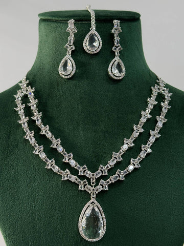 Silver Plated American Diamond Necklace Set with teardrop pendant and matching earrings on green display