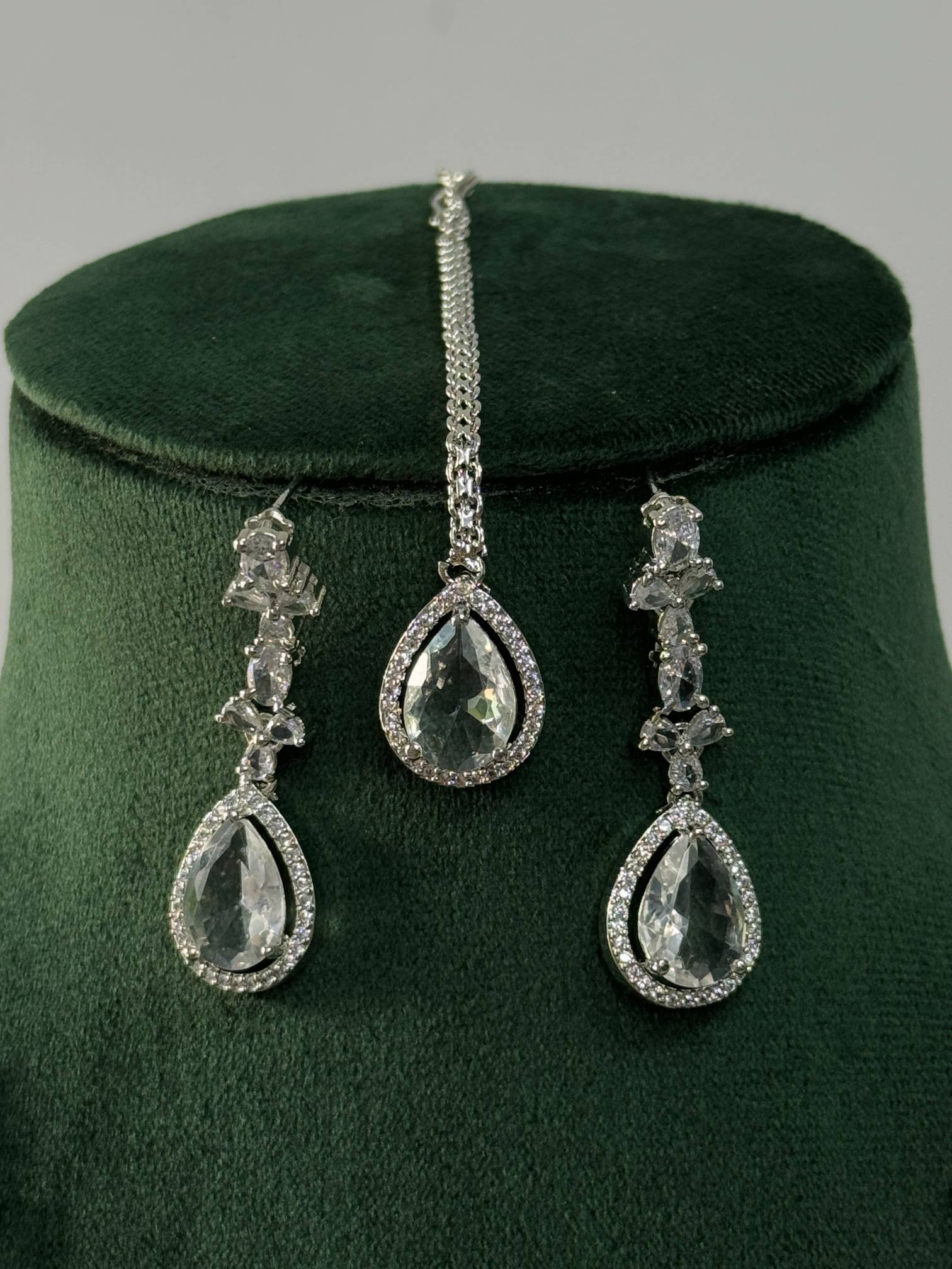 Silver Plated American Diamond Necklace Set with teardrop-shaped pendants displayed on green velvet stand