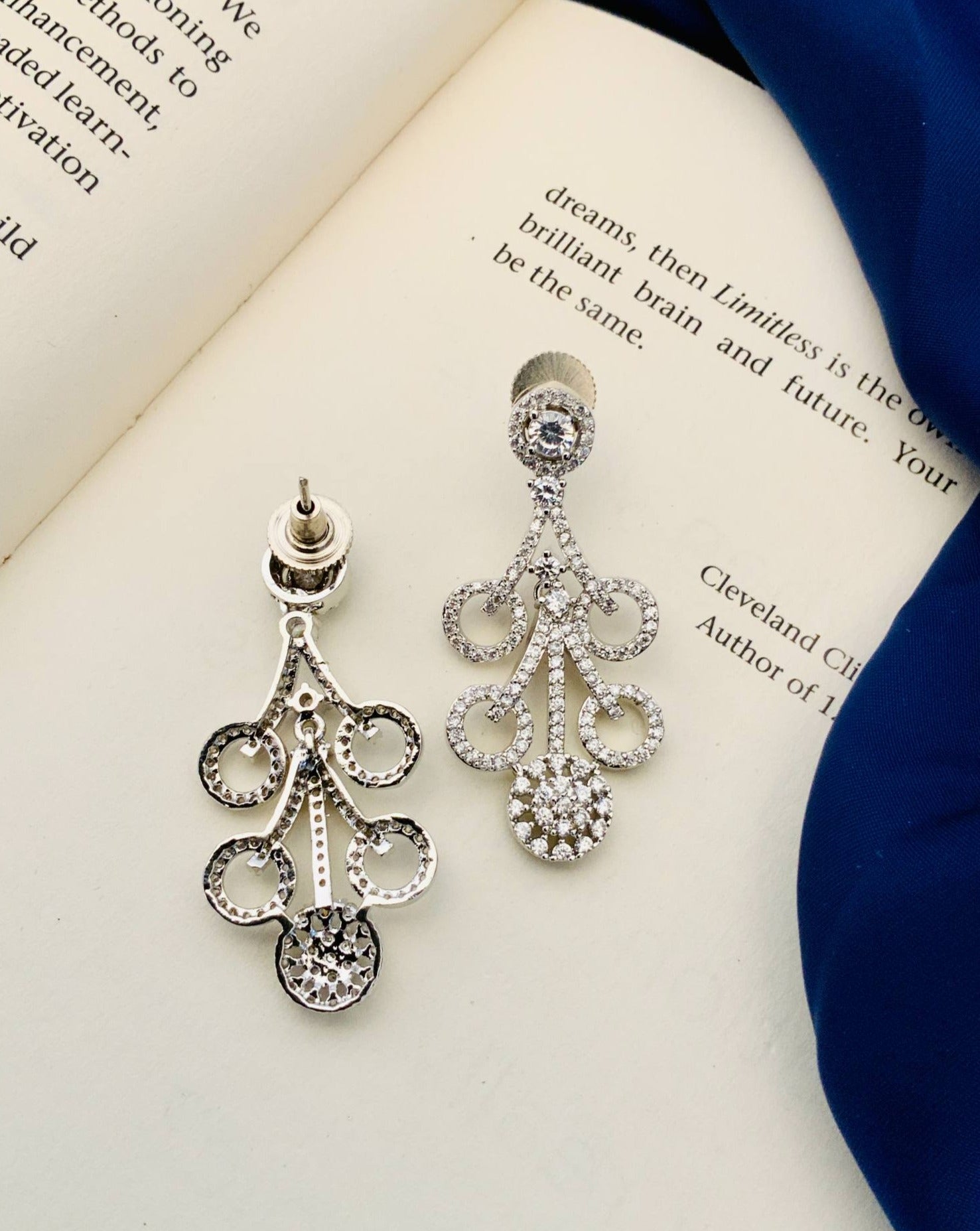 Silver Plated American Diamond Necklace Set earrings with intricate design on an open book background
