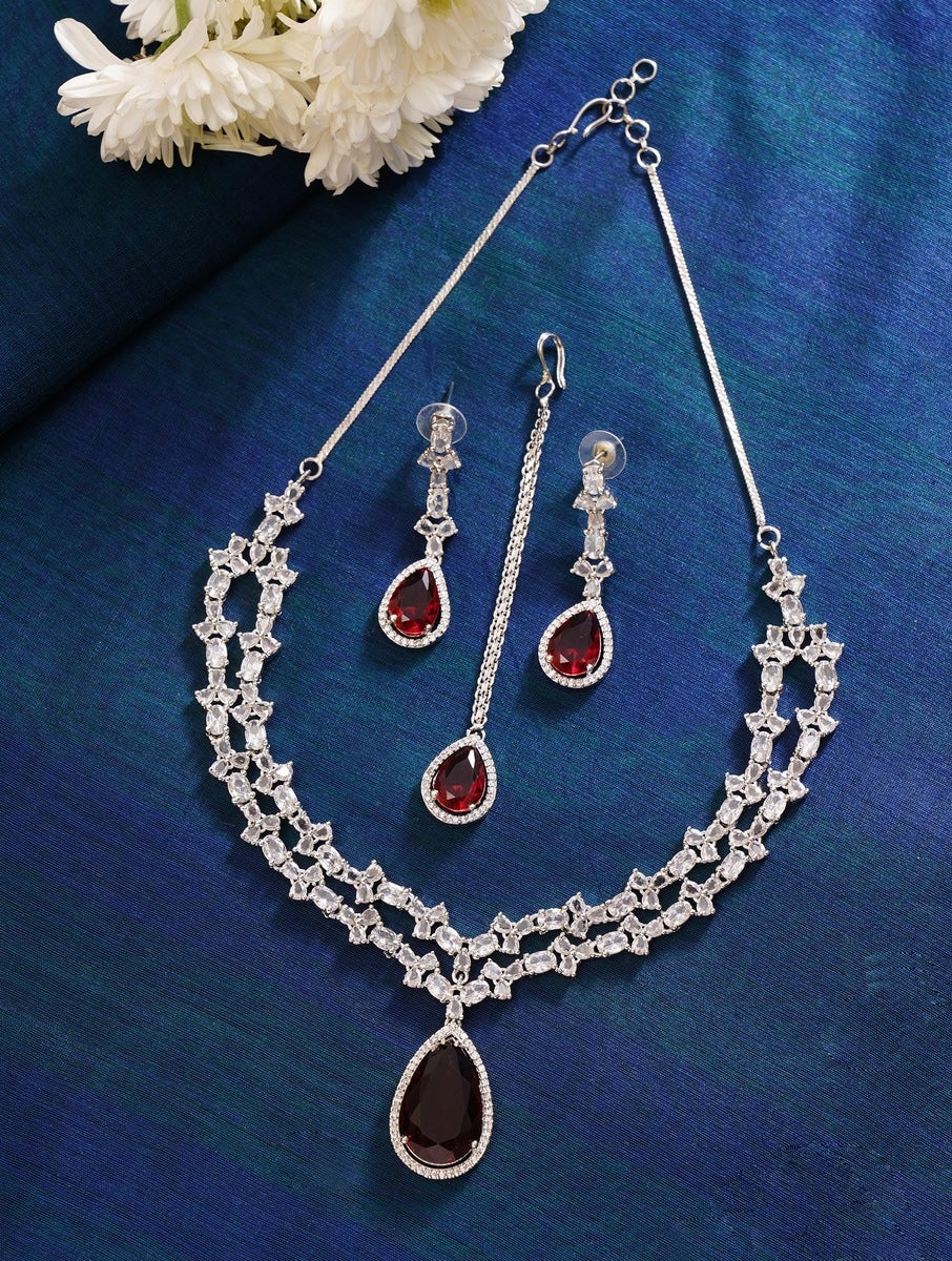 Silver Plated American Diamond Necklace Set with red teardrop stones and matching earrings on blue background
