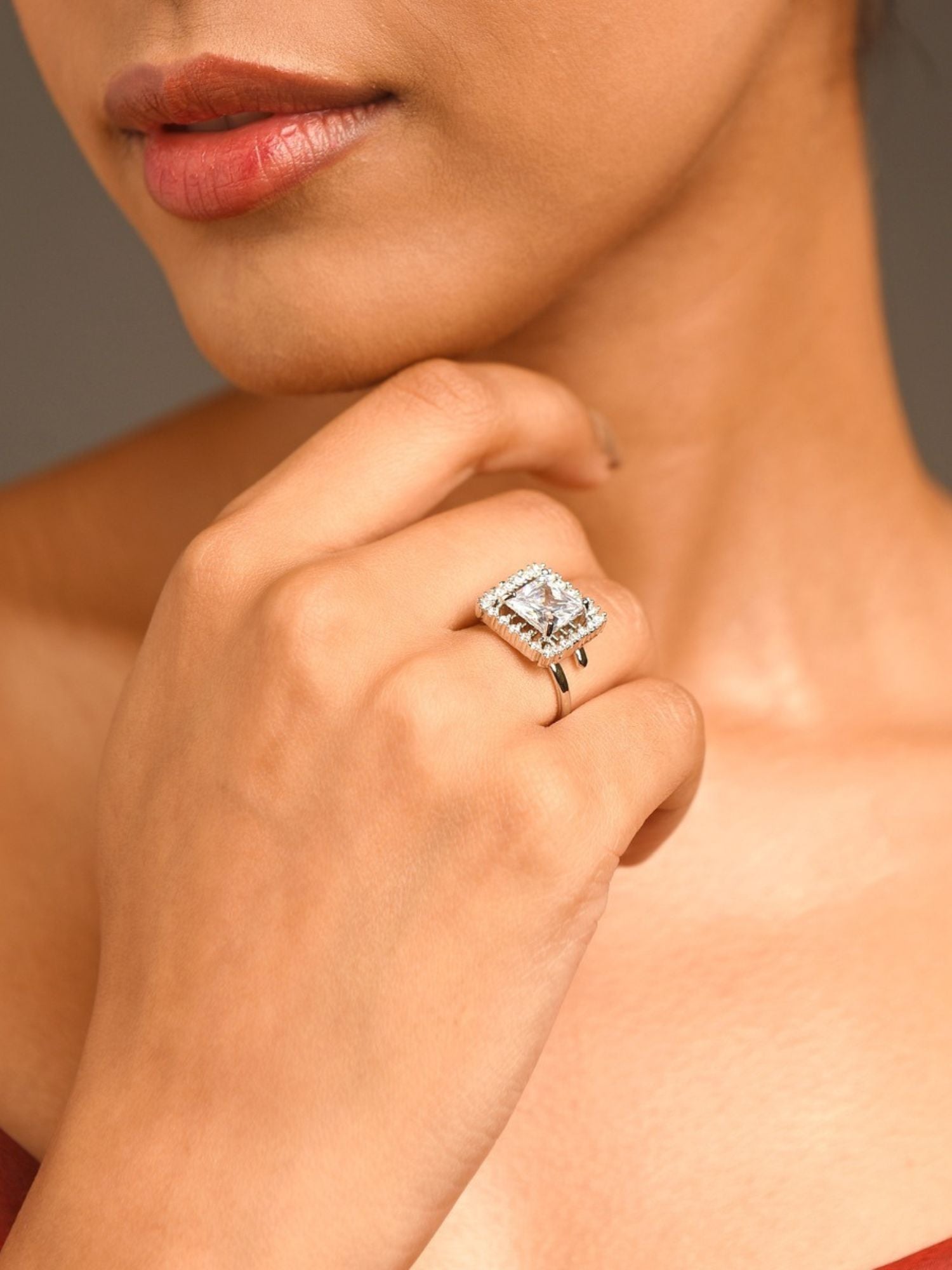 Close up of a woman wearing silver plated American diamond square ring with halo setting