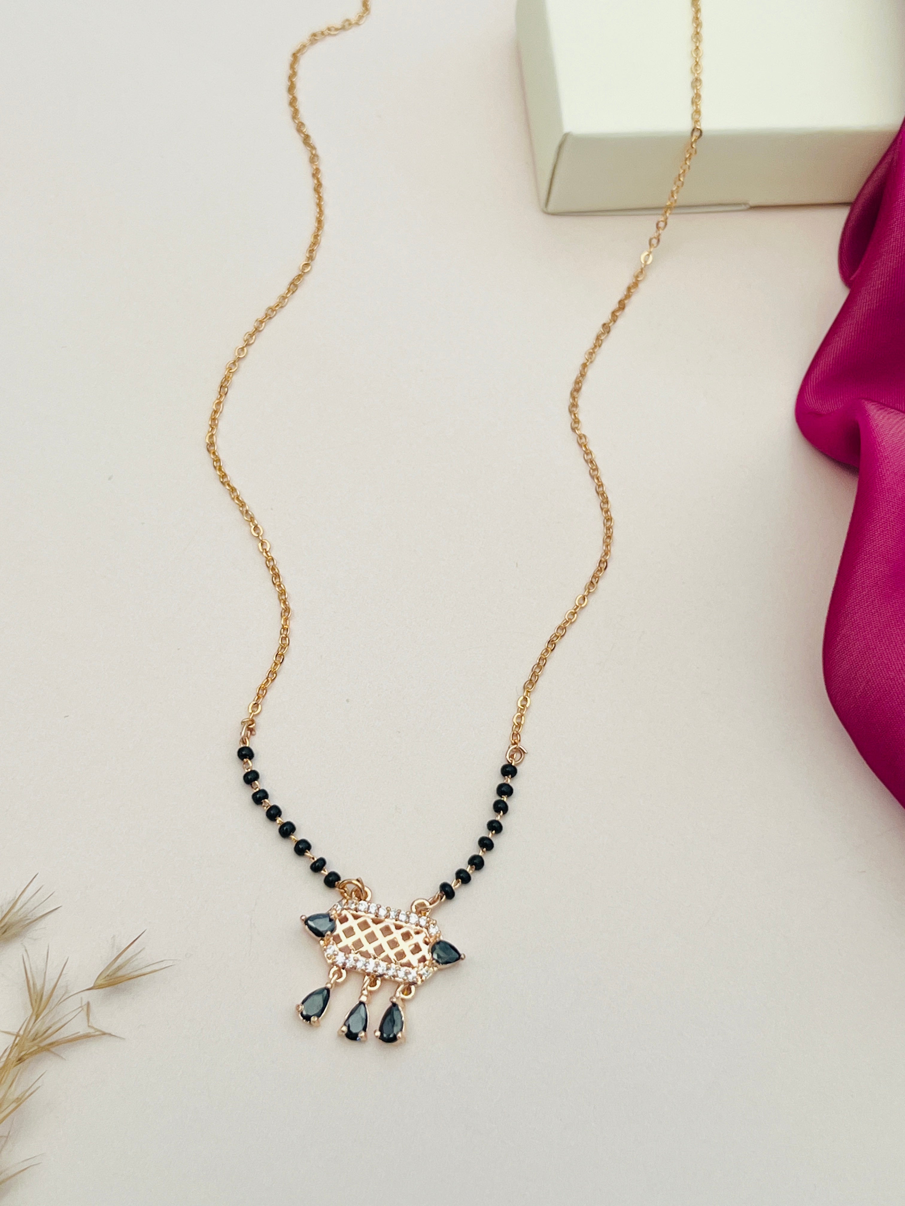 Abdesignsjewellery American Diamond Mangalsutra with black beads and gold pendant on white 