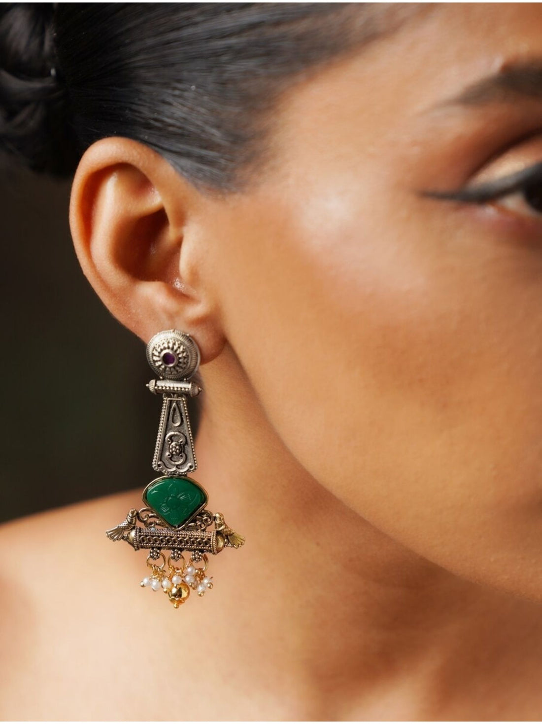 Abdesignsjewellery Dual Tone Bird Stone Earrings with green stone and intricate metalwork worn on ear