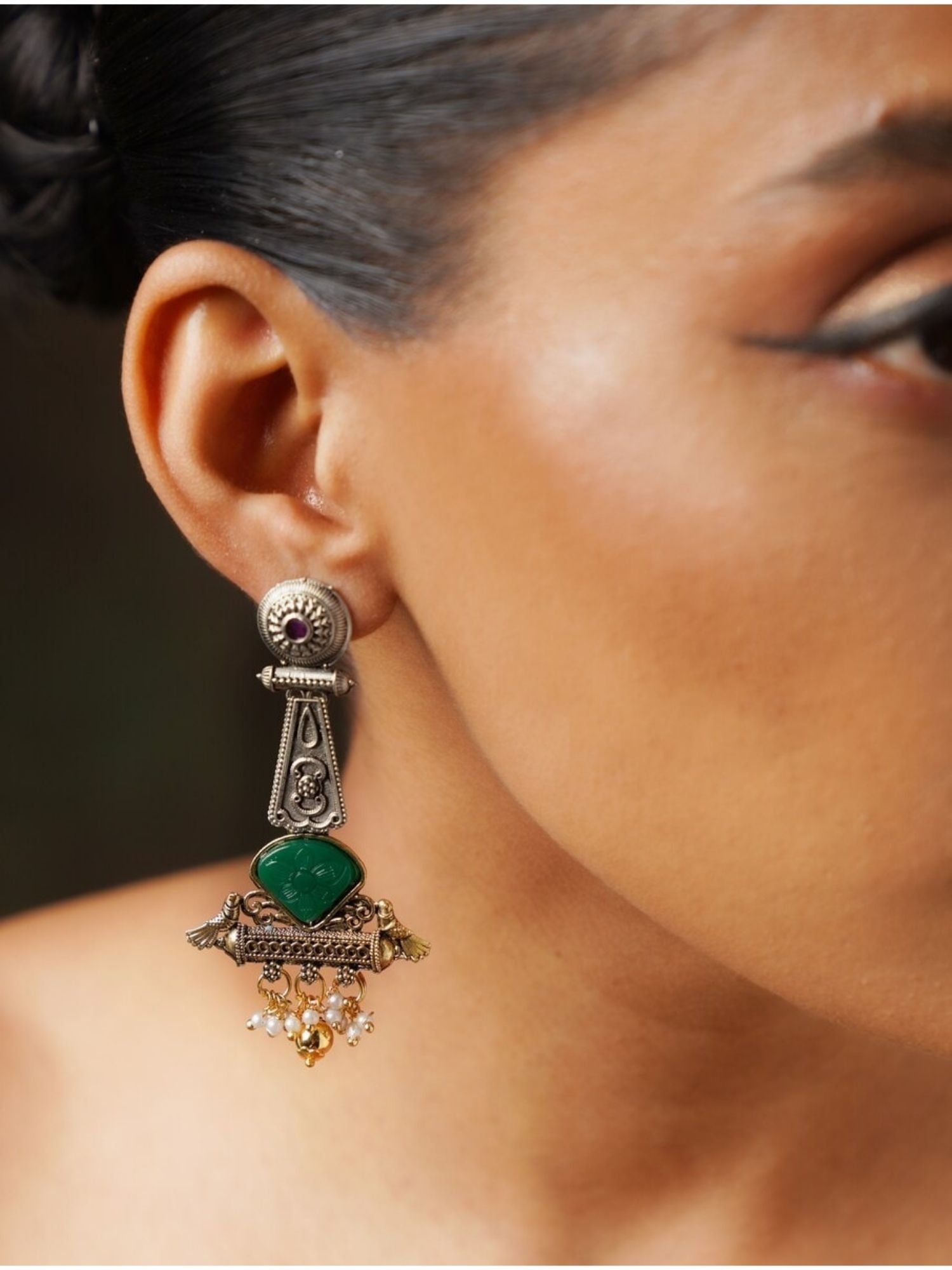 Abdesignsjewellery Dual Tone Bird Stone Earrings with green stone and intricate metalwork worn on ear