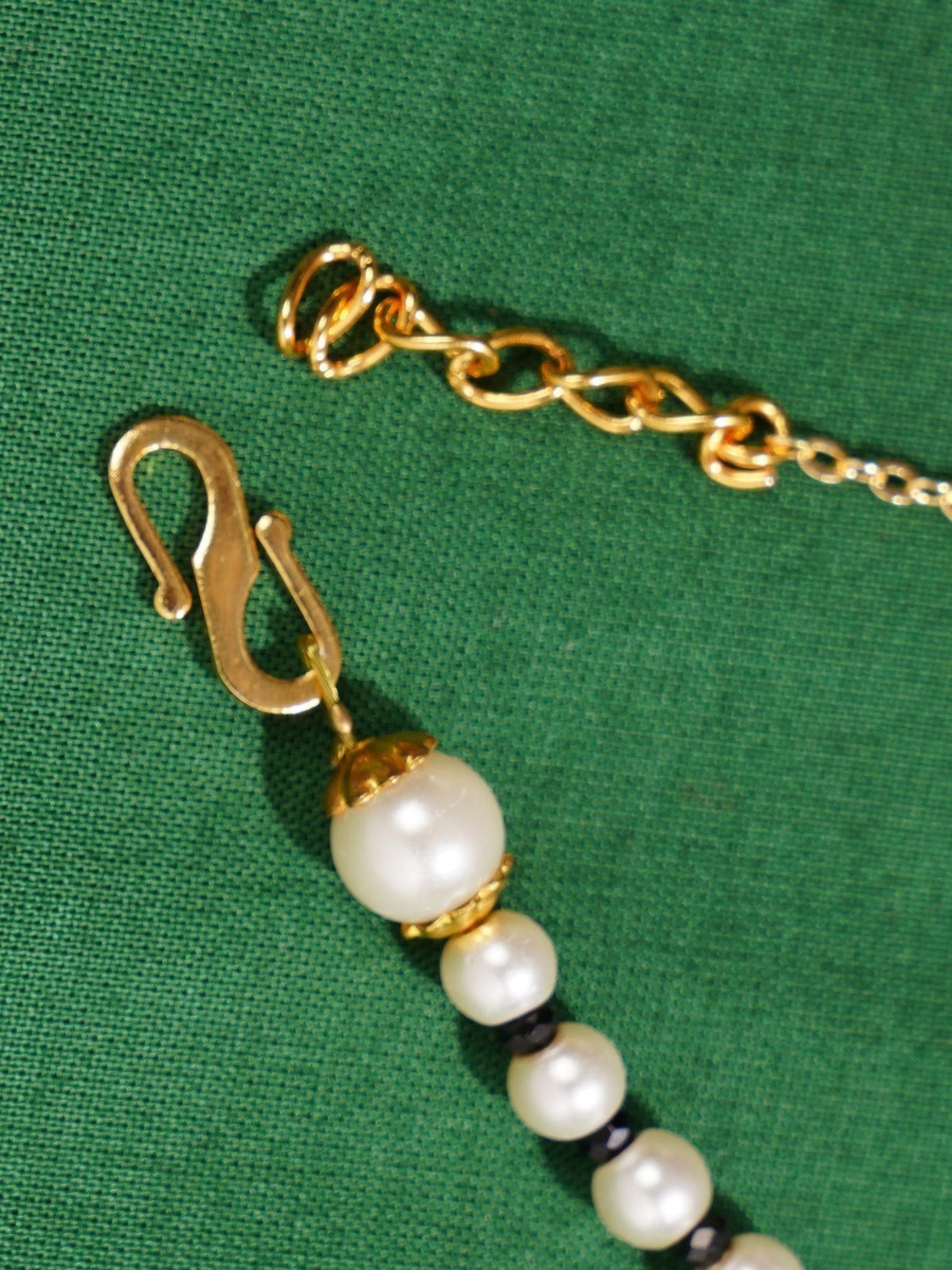 Ethnic Gold Plated Pearls Foot Anklets with gold chain and pearl beads on green background
