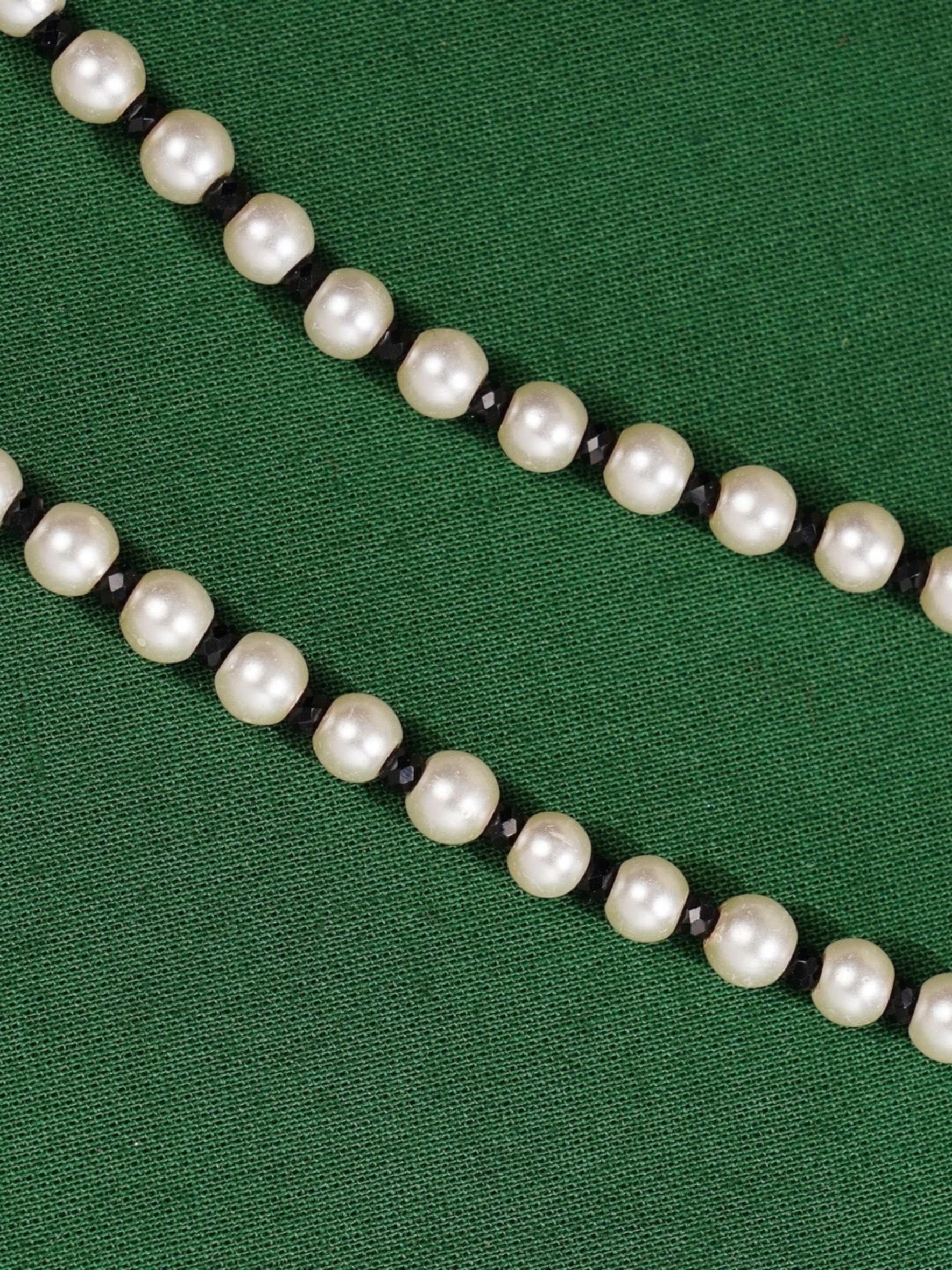 Ethnic Gold Plated Pearls Foot Anklets with white pearls and black beads on green background