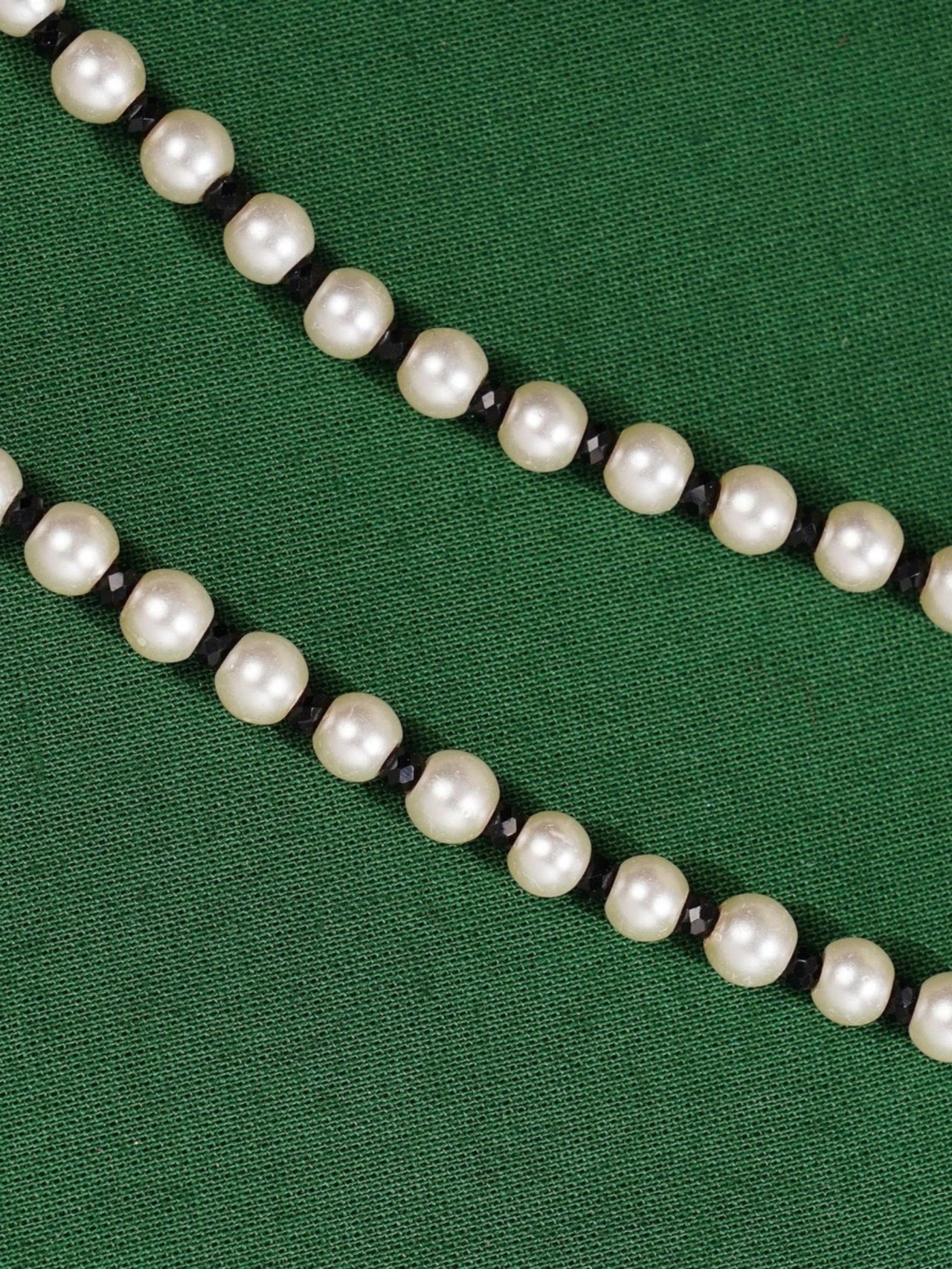 Ethnic Gold Plated Pearls Foot Anklets with white pearls and black beads on green background