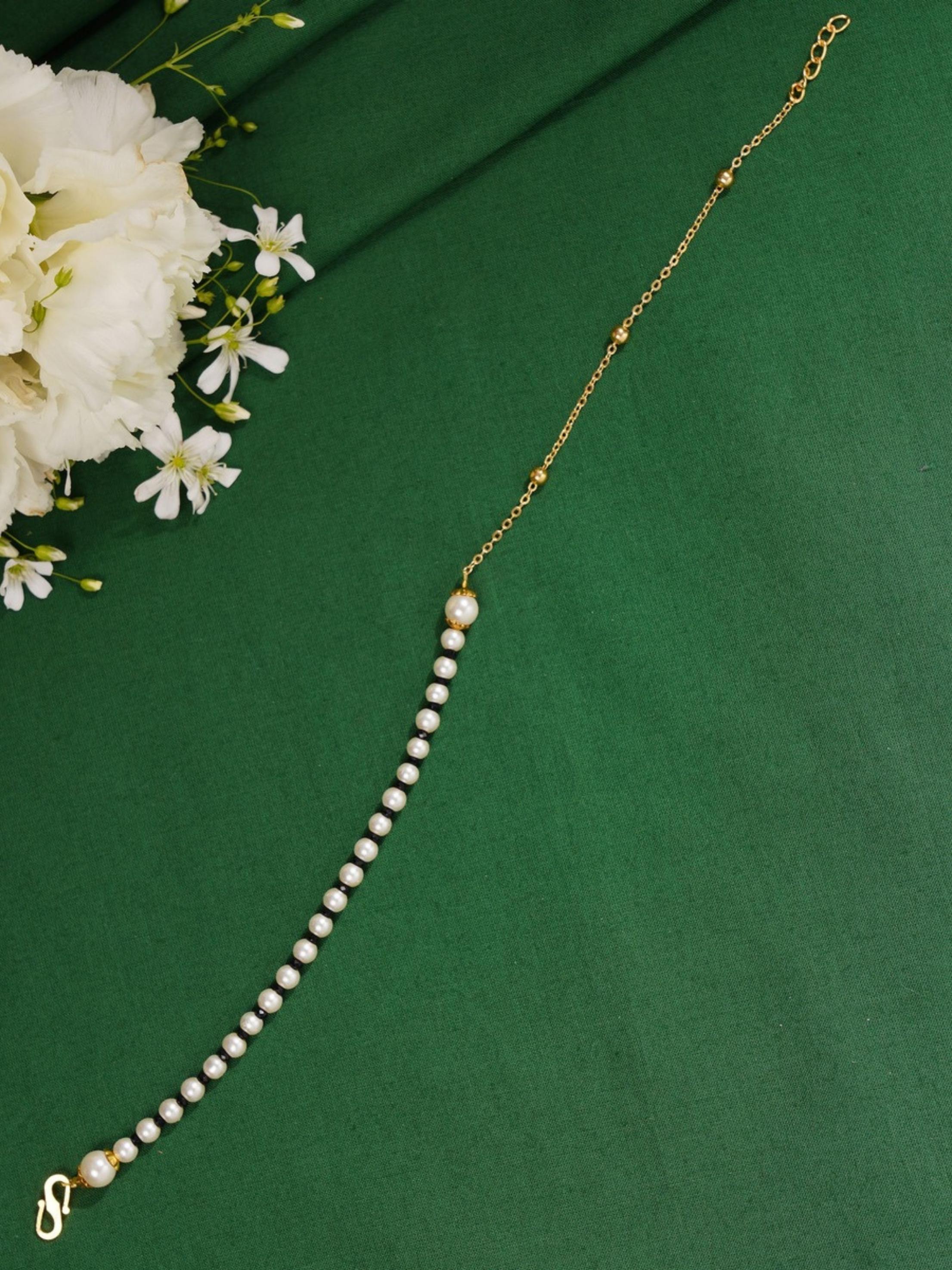 Ethnic Gold Plated Pearls Foot Anklets with white pearls and gold chain on green background