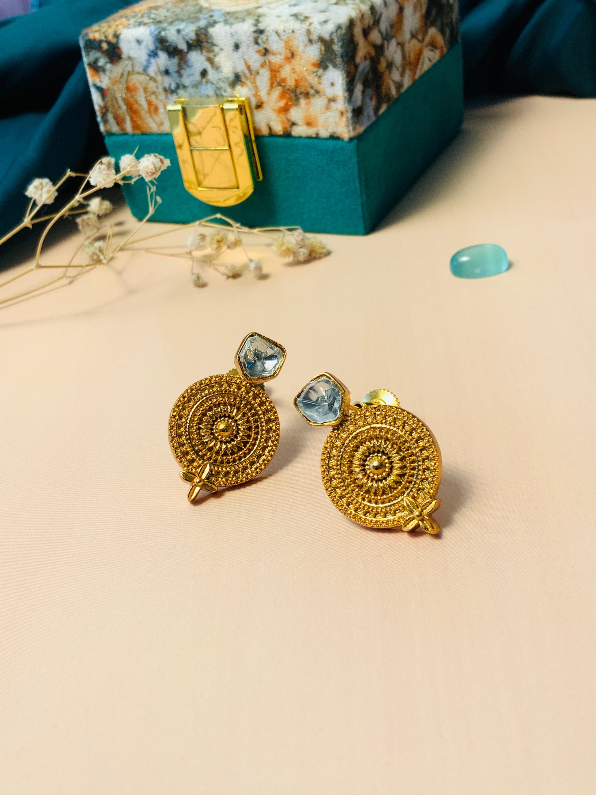 Gold Plated Glass Kundan Polki Stud Earrings with intricate circular design placed on beige surface