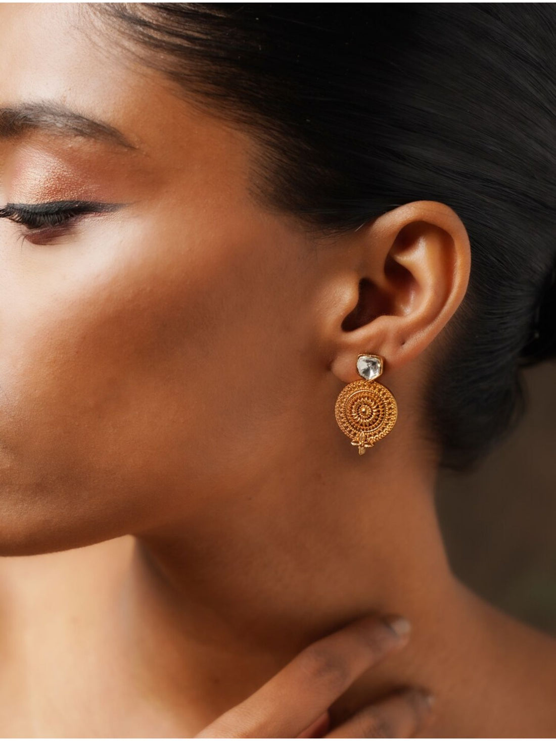 Close-up of a woman wearing Gold Plated Glass Kundan Polki Stud Earrings with intricate circular design