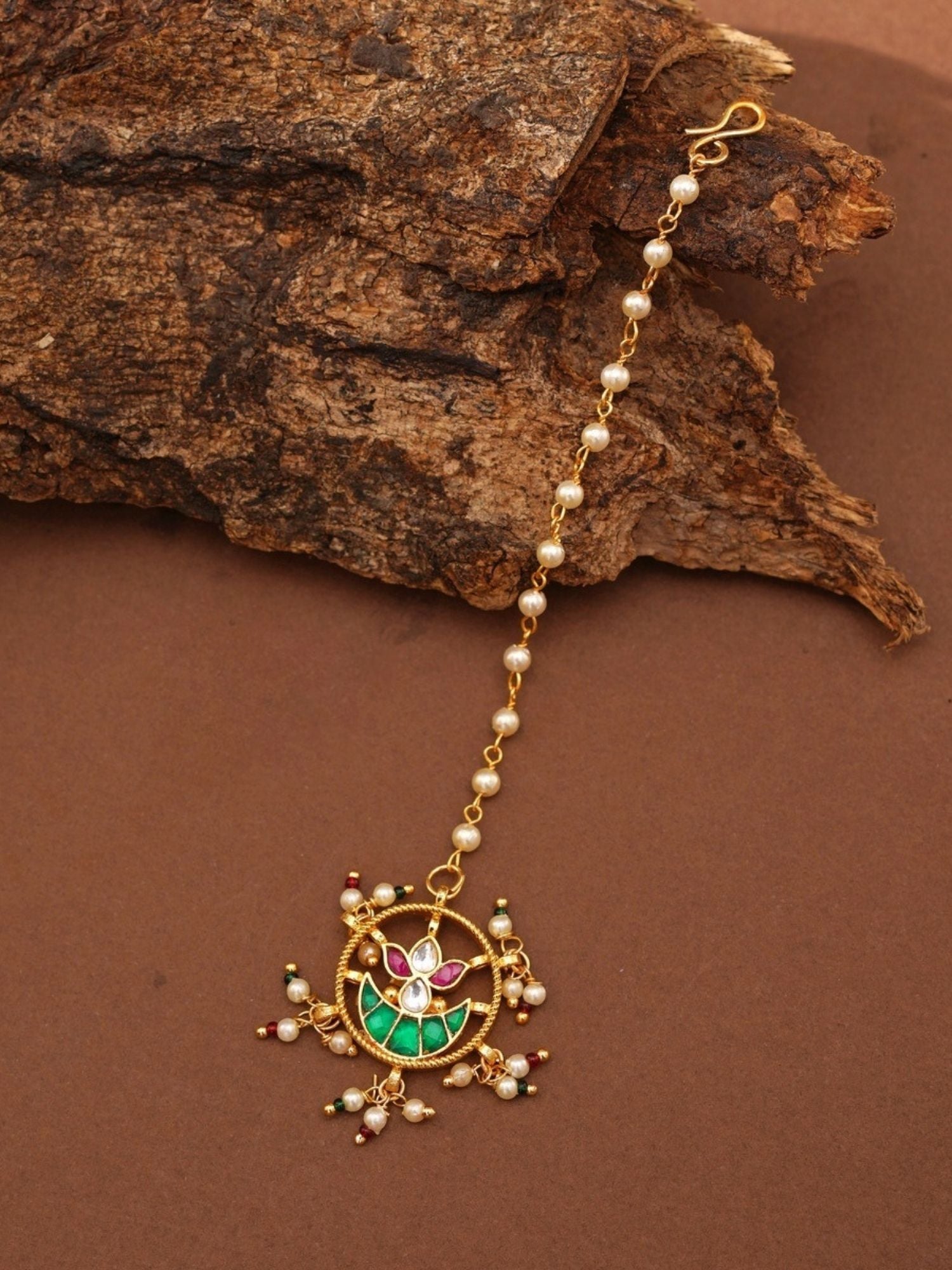 Gold Plated Paachi Kundan Maangtikka with pearl beads and colorful stones on a brown surface
