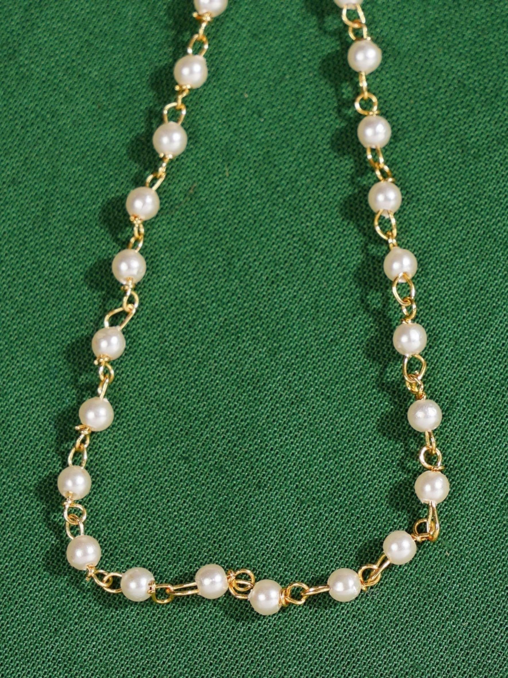 Gold Plated Polki Hand Bracelet with white pearls and delicate gold links on green background