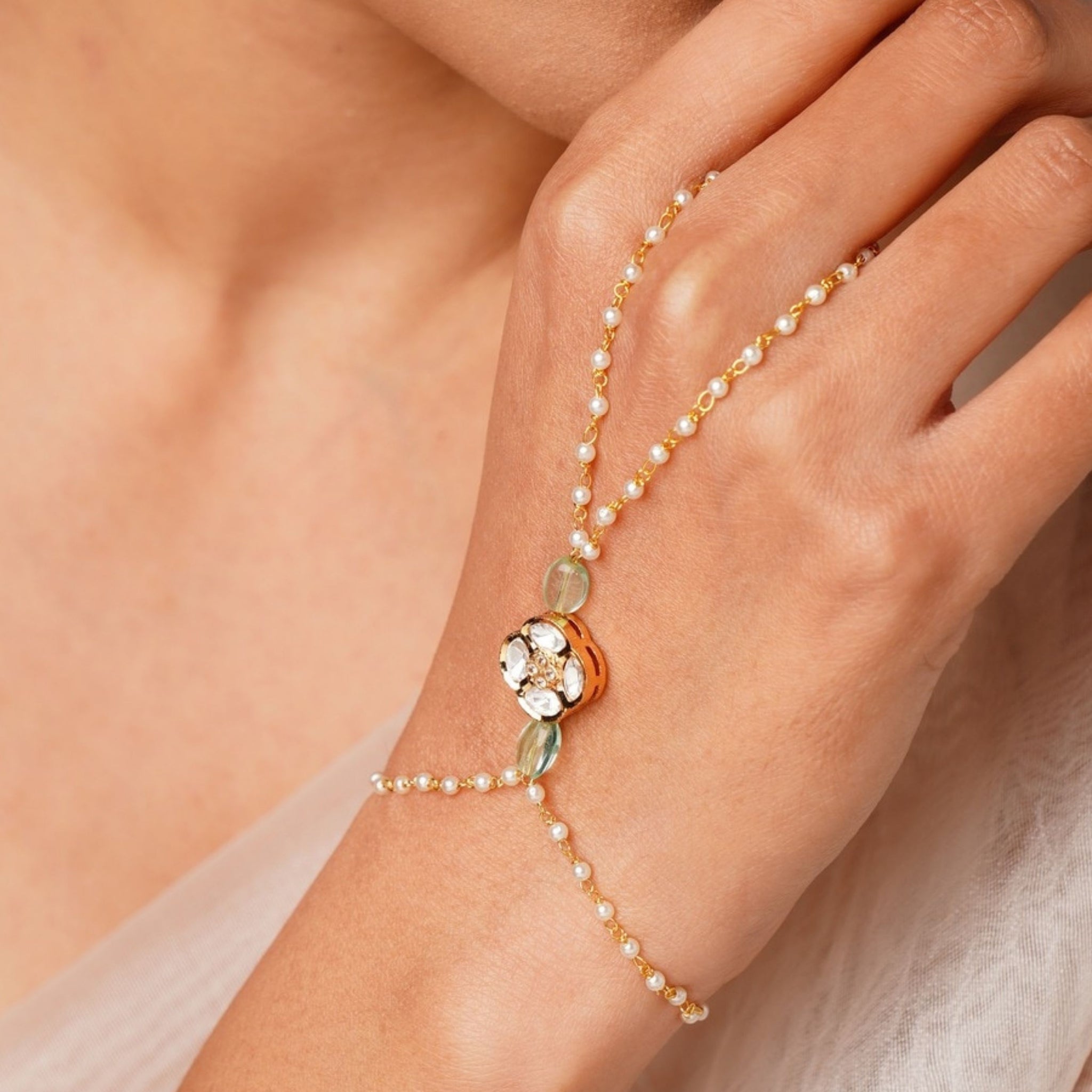 Gold Plated Polki Hand Bracelet with pearls and gemstones worn on hand by woman