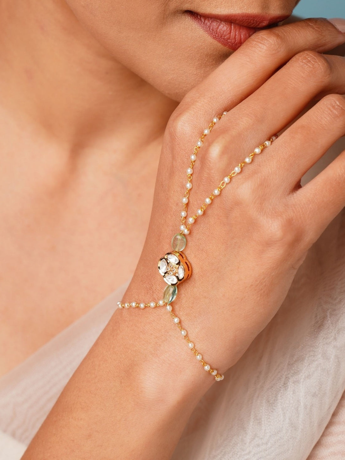 Gold Plated Polki Hand Bracelet with pearls and gemstones worn on hand by woman
