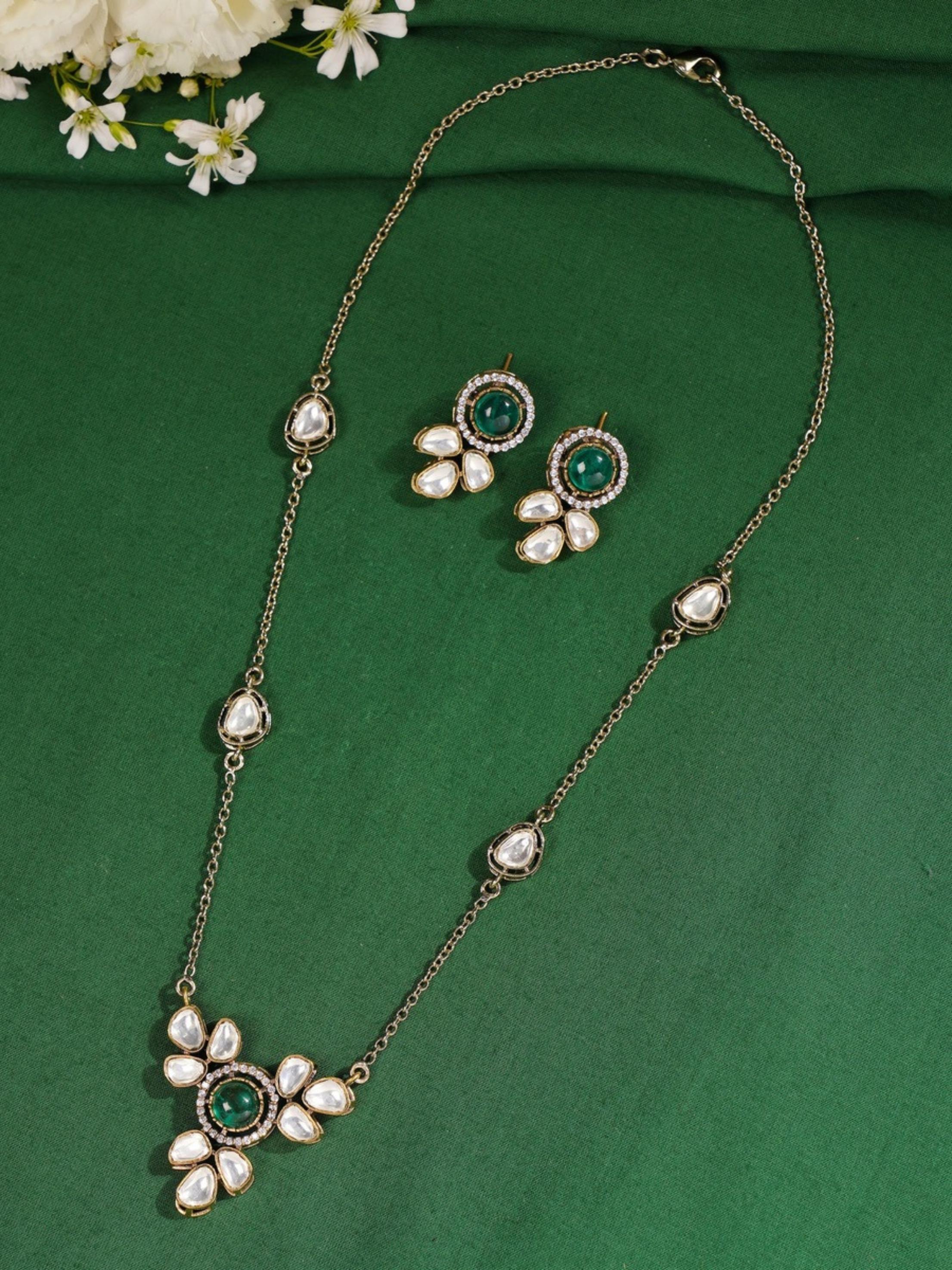 Green Emerald Statement Oxidsed Gold Polki Necklace Set with matching earrings on green background