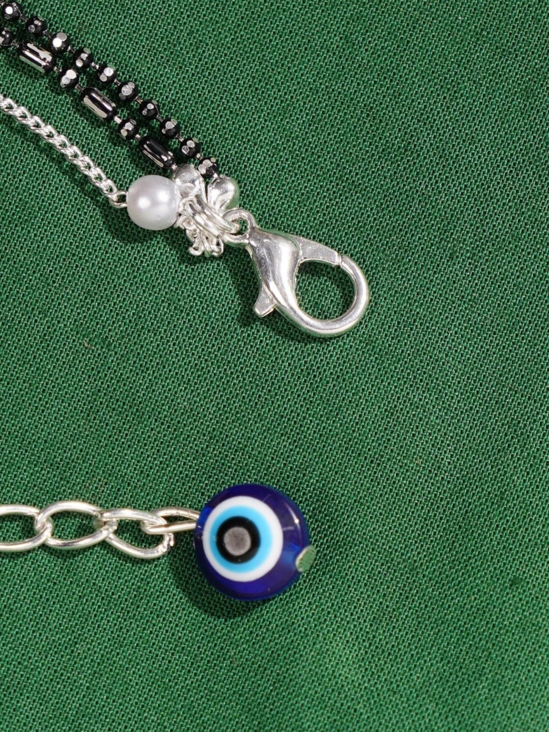 Handcrafted Silver Evil Eye Foot Jewelry Anklet with blue evil eye charm and silver clasp on green fabric