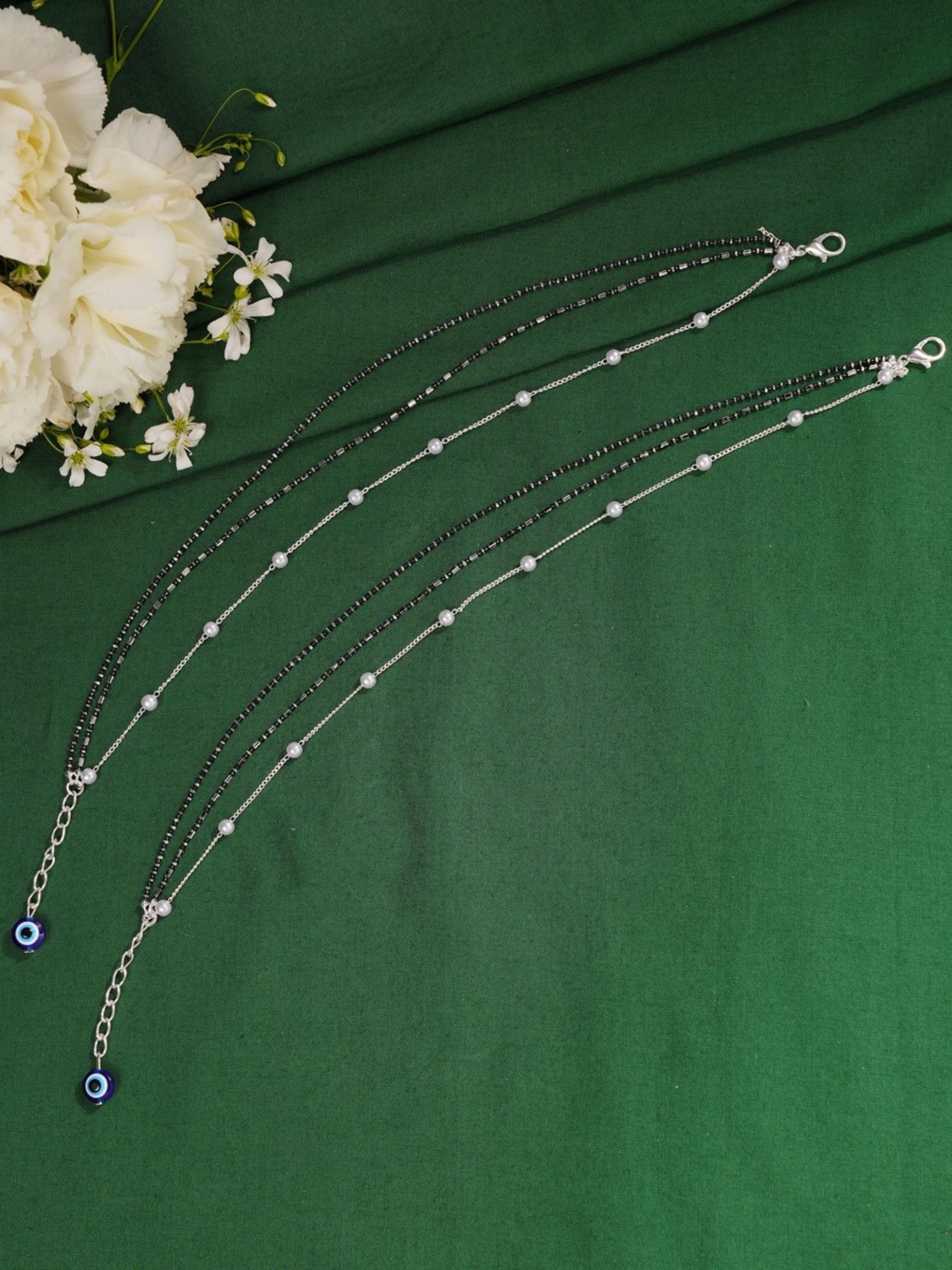 Handcrafted Silver Evil Eye Foot Jewelry Anklet combo with delicate chains and blue eye charms on green background