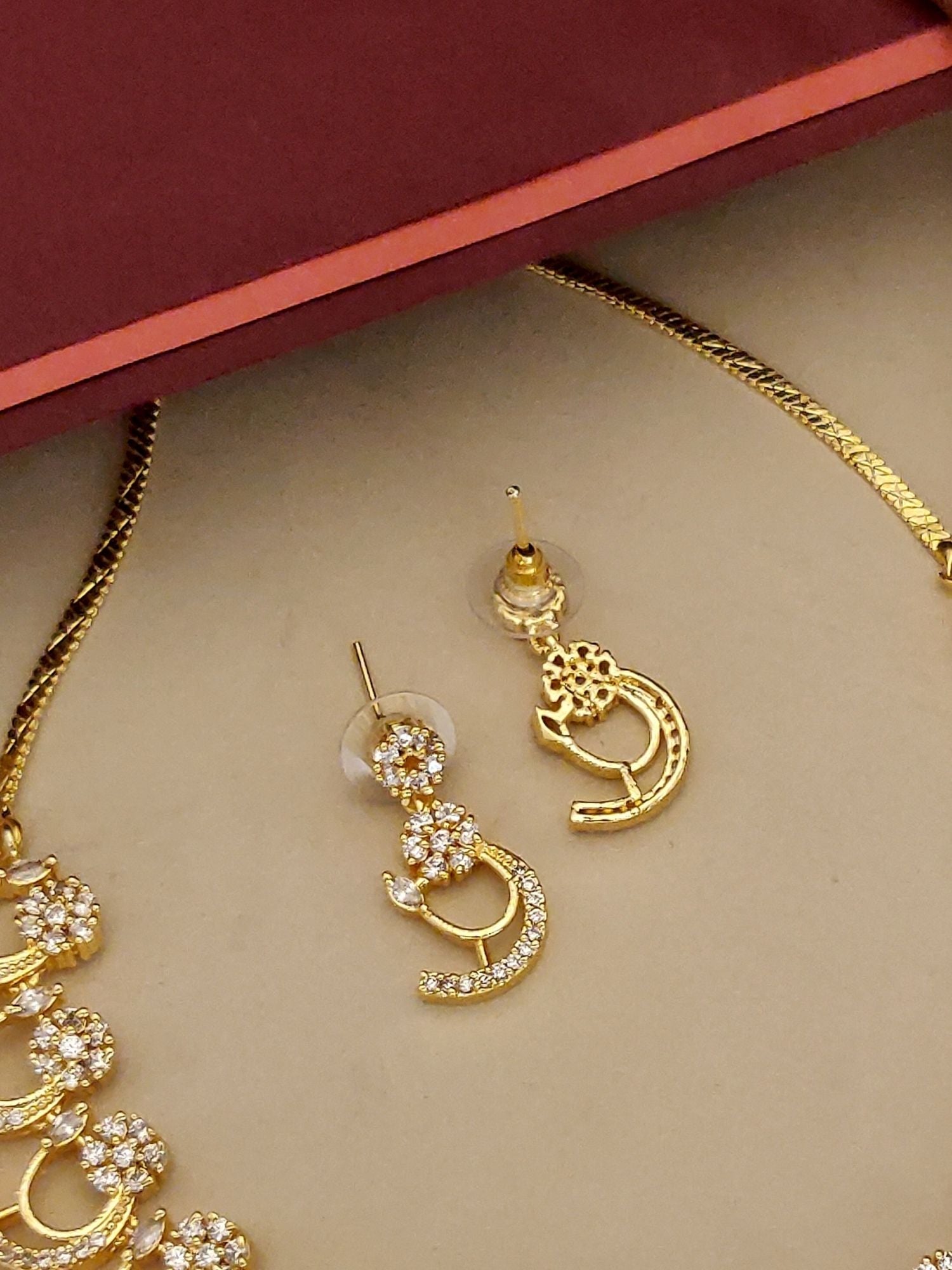 Abdesignsjewellery gold pendant chain with matching crescent stud earrings American diamond necklace set on beige background