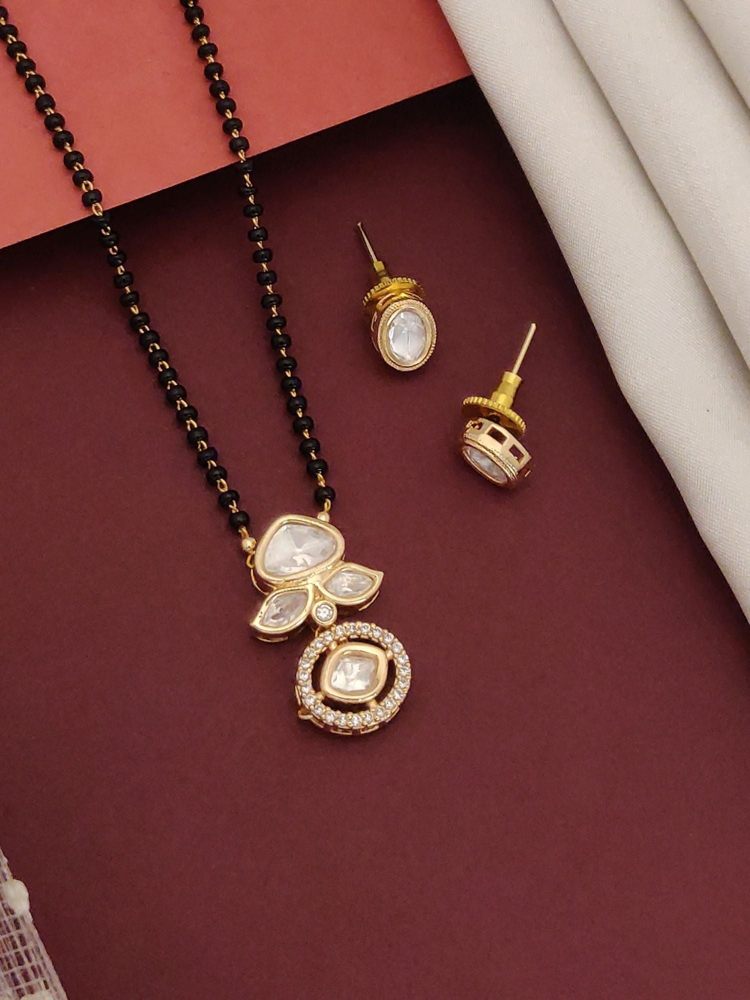 Bollywood style polki mangalsutra set with black beads and gold pendant featuring white polki stones and matching earrings