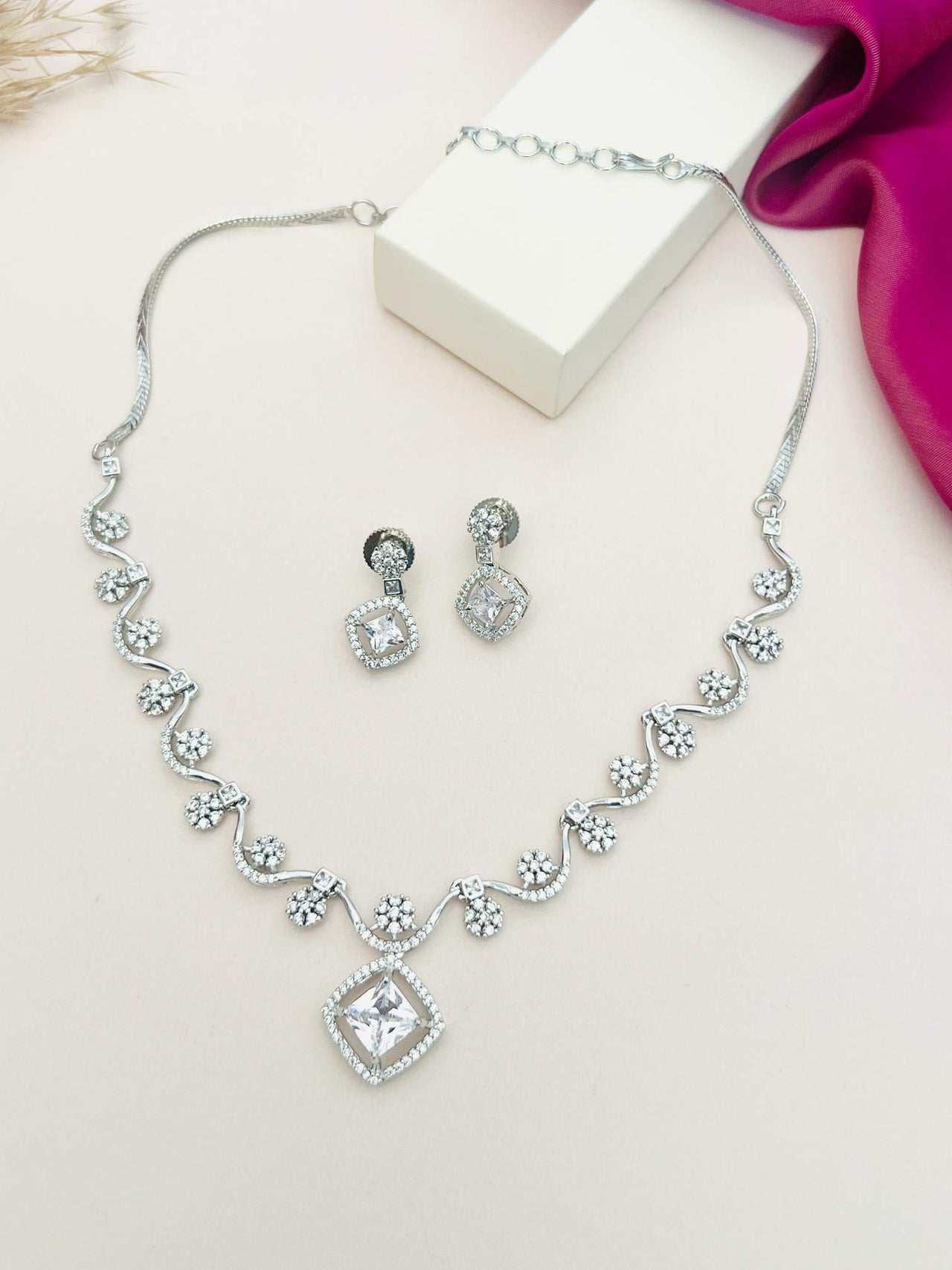 Elegant Necklace with Sparkling Stones and matching earrings by Abdesignsjewellery displayed on white and pink background