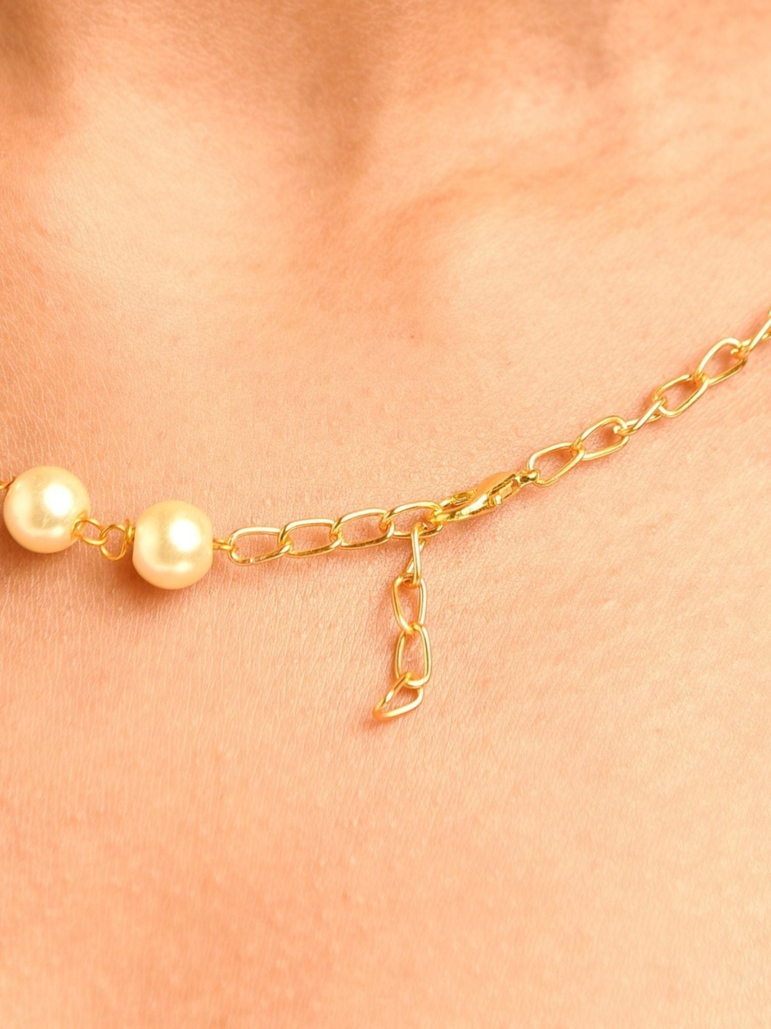 Close up of model neckline wearing gold plated beaded necklace set with two pearl beads and adjustable chain