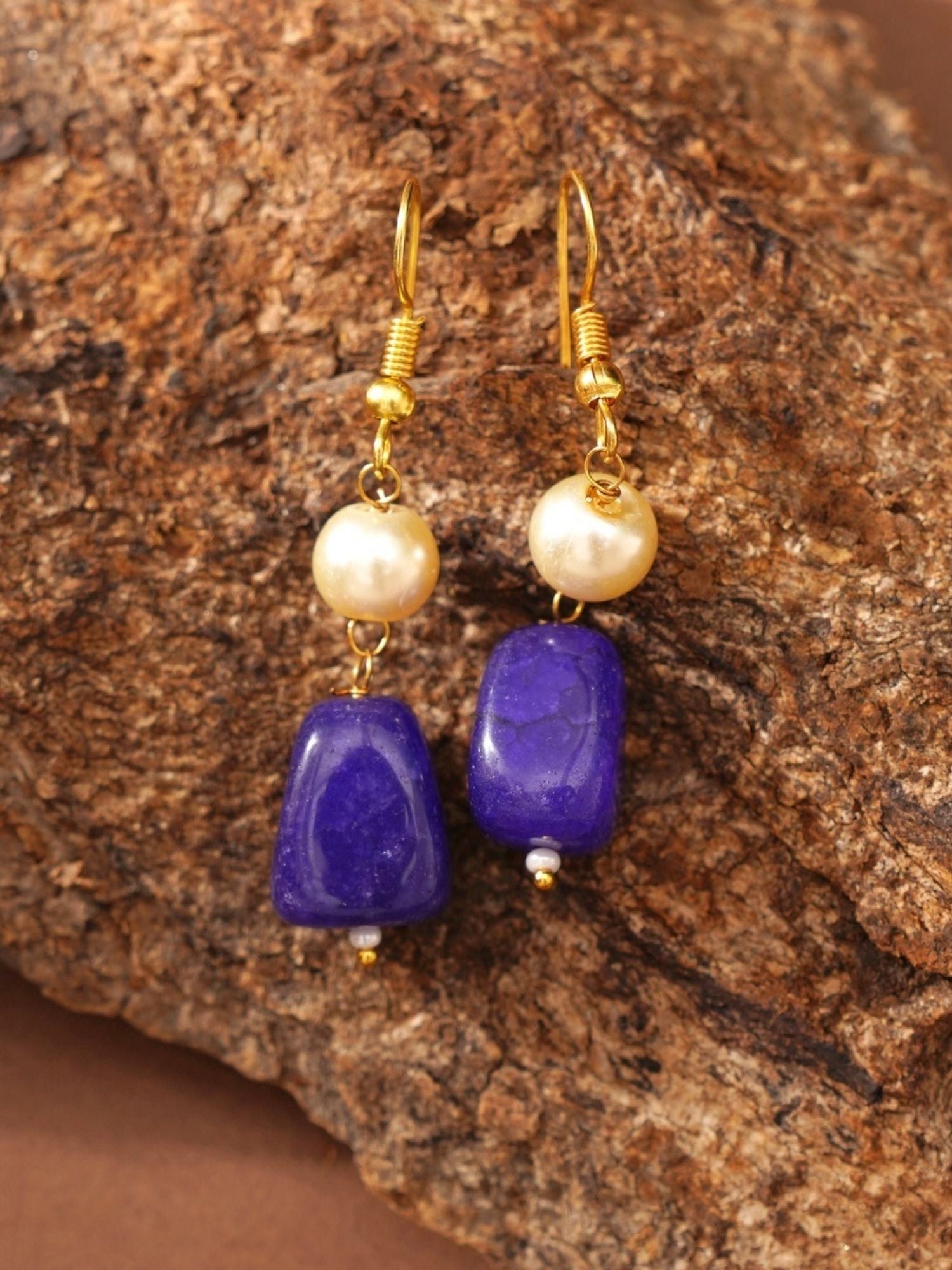 Abdesignsjewellery gold plated beaded necklace set styled with matching purple stone and pearl drop earrings on textured rock