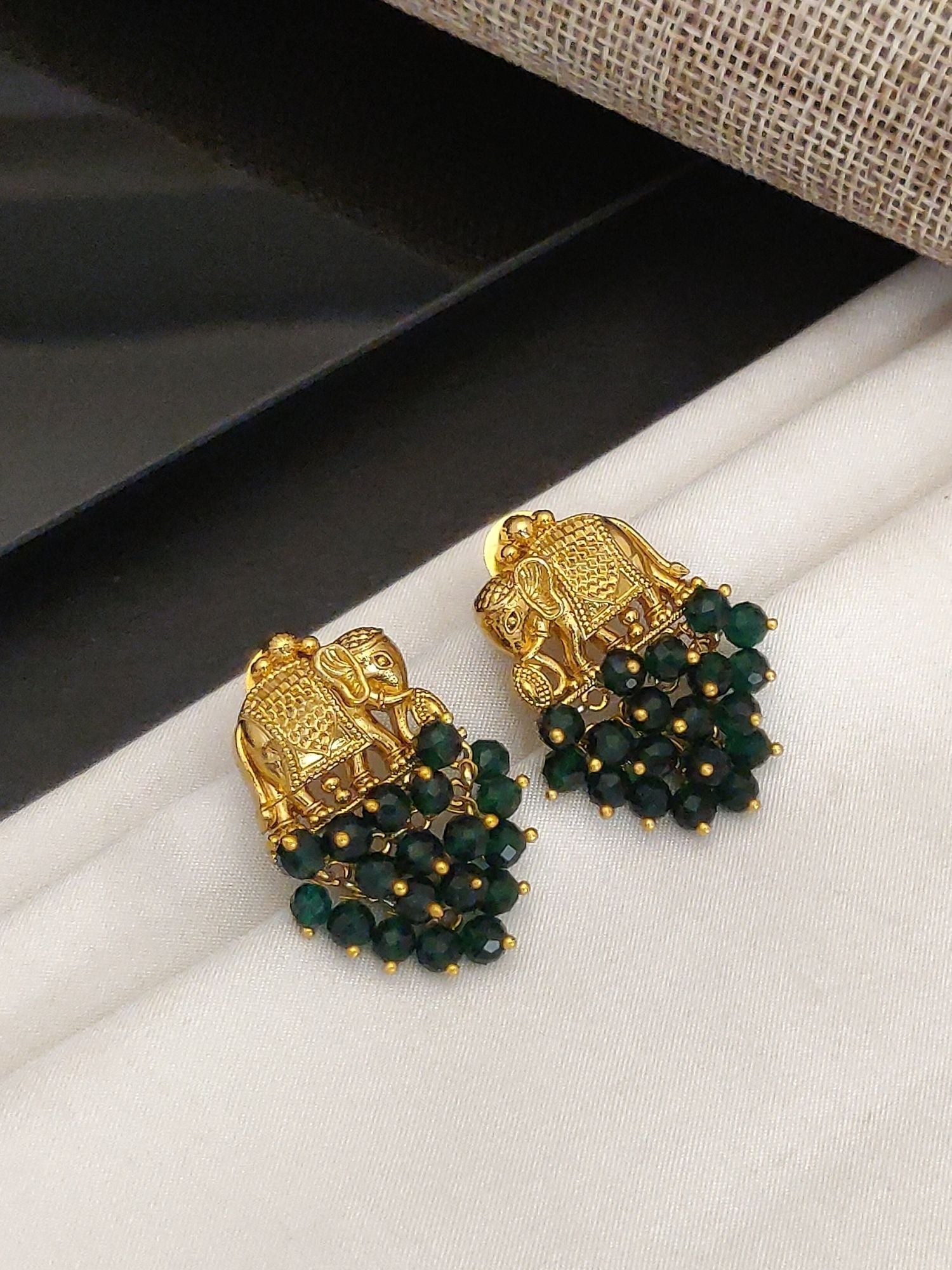 Abdesignsjewellery gold plated elephant earrings with green bead detailing on white fabric background