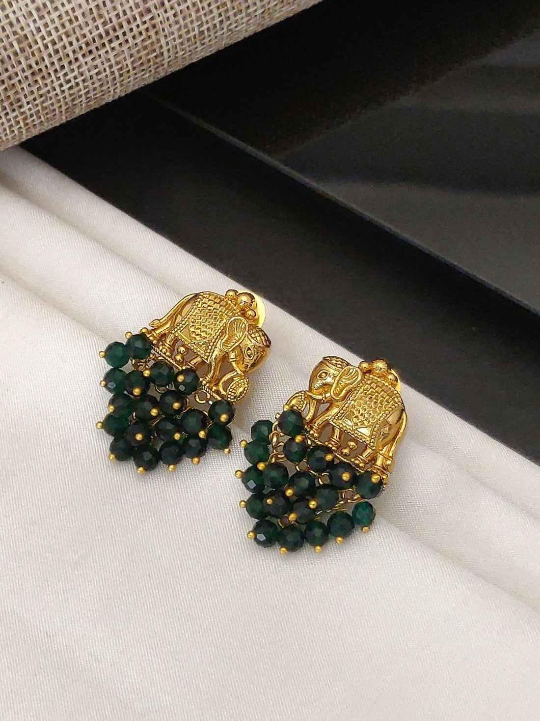 Abdesignsjewellery gold plated elephant earrings with green bead detailing on white fabric background