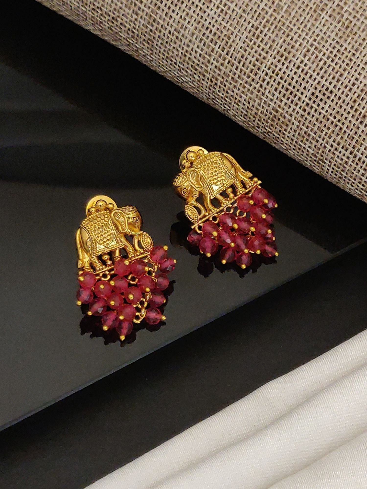 Gold plated elephant earrings with intricate elephant design and red bead dangles by Abdesignsjewellery