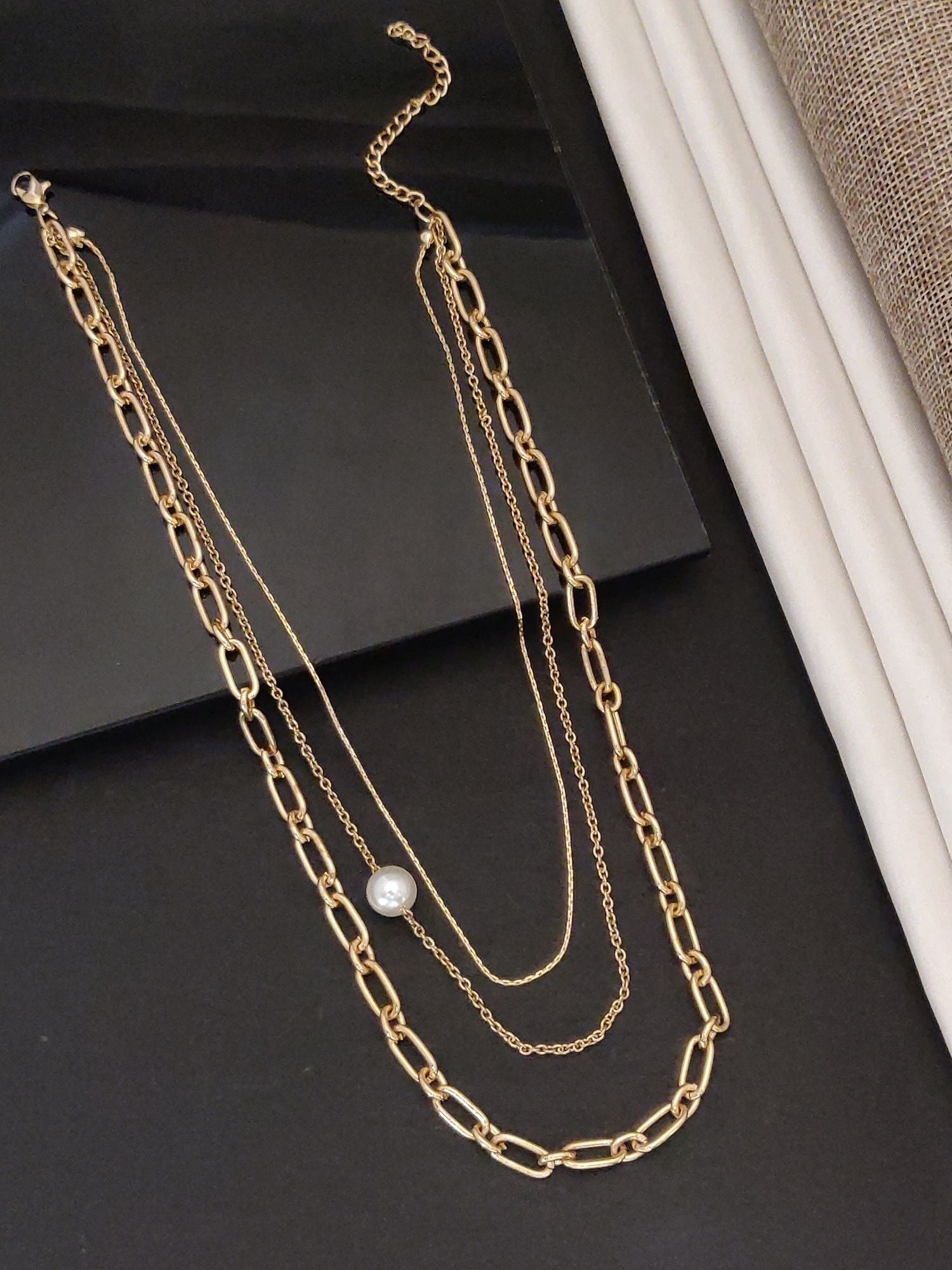 Elegant gold plated layered necklace featuring delicate chains and a pearl accent for a stylish look