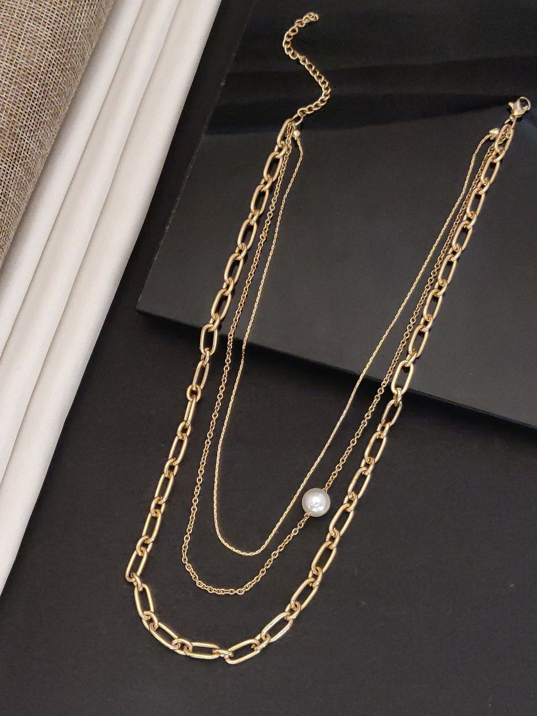 Elegant gold plated layered necklace featuring delicate chains and a pearl accent for a stylish look