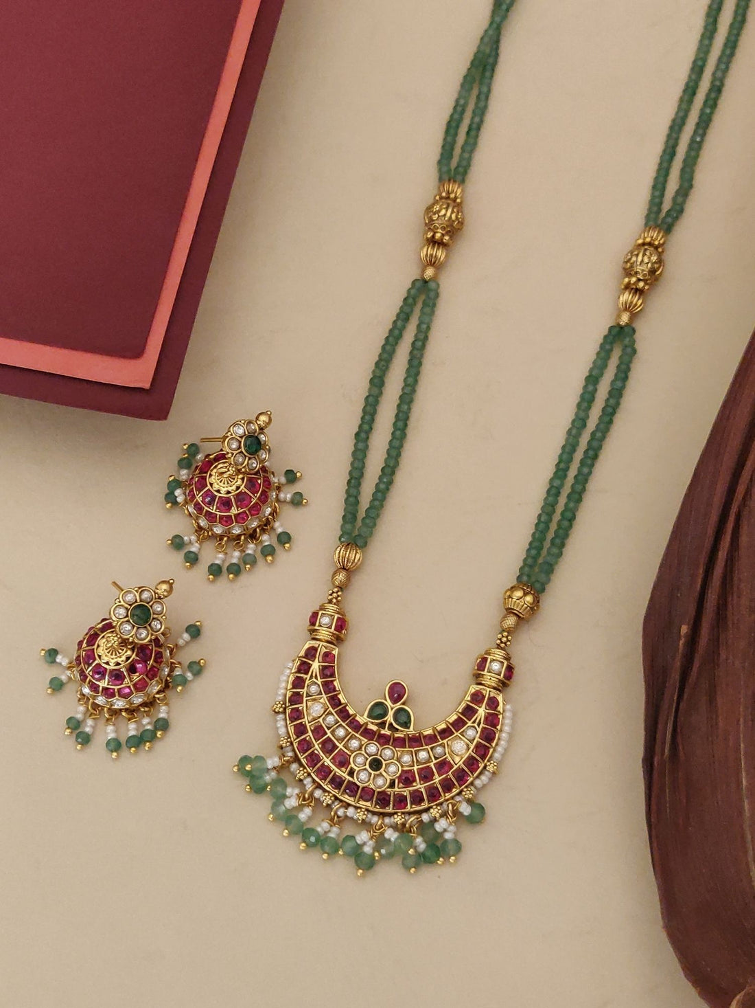 Gold plated long necklace with vibrant red and green stones, paired with matching earrings