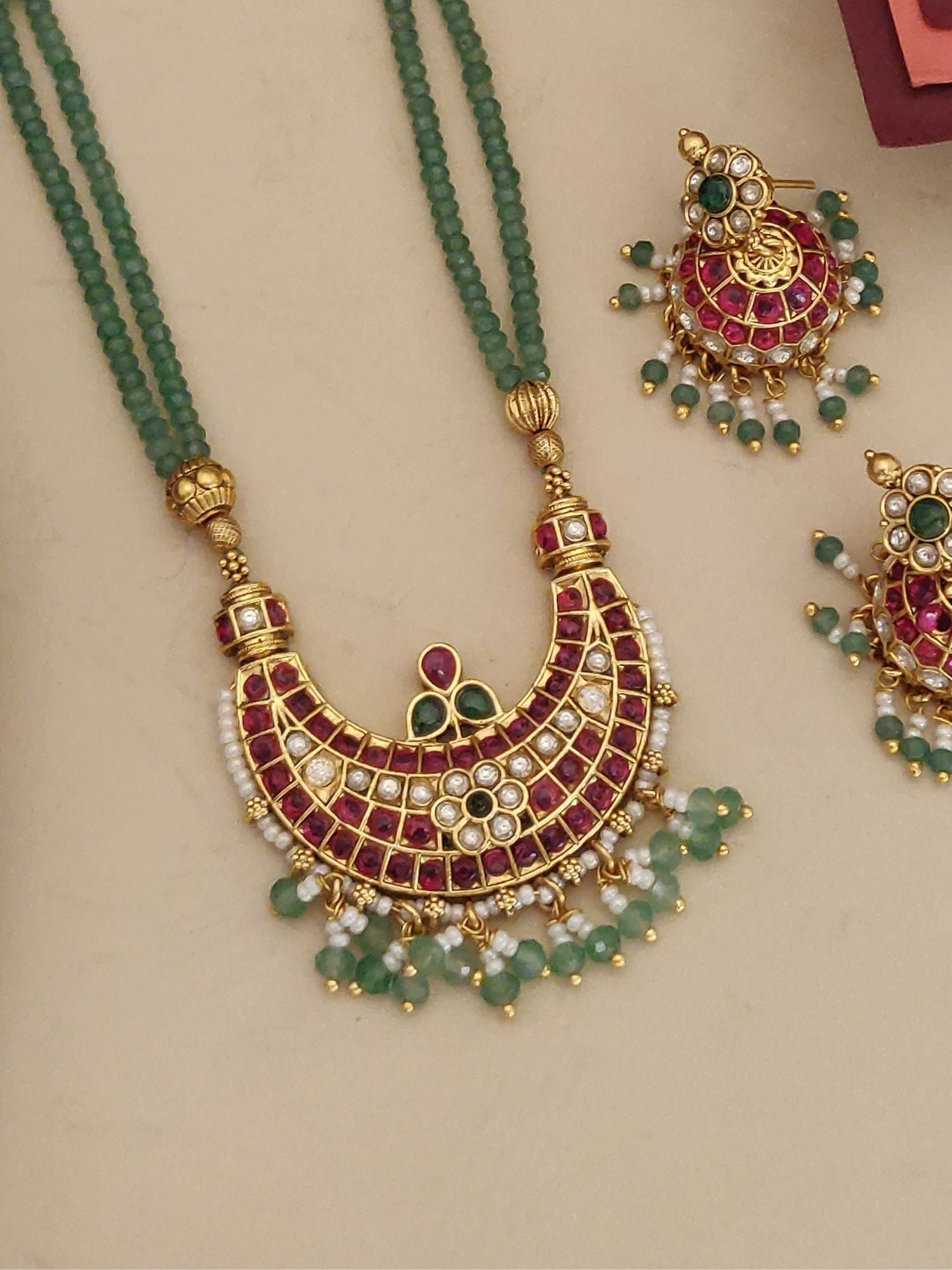 Gold plated long necklace with intricate design and colorful gemstones, paired with matching earrings