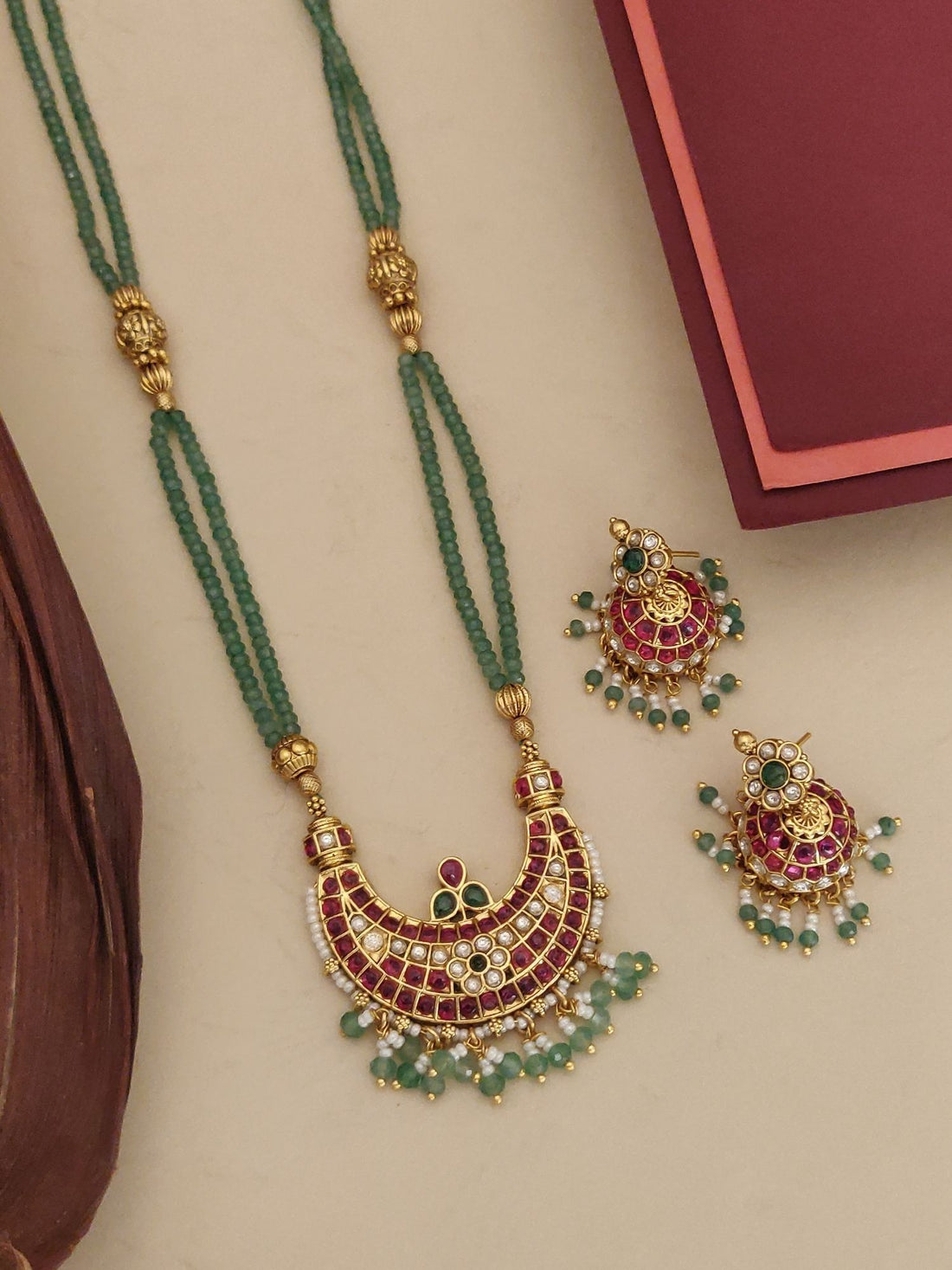 Gold plated long necklace with intricate design and green beads, perfect for festive occasions