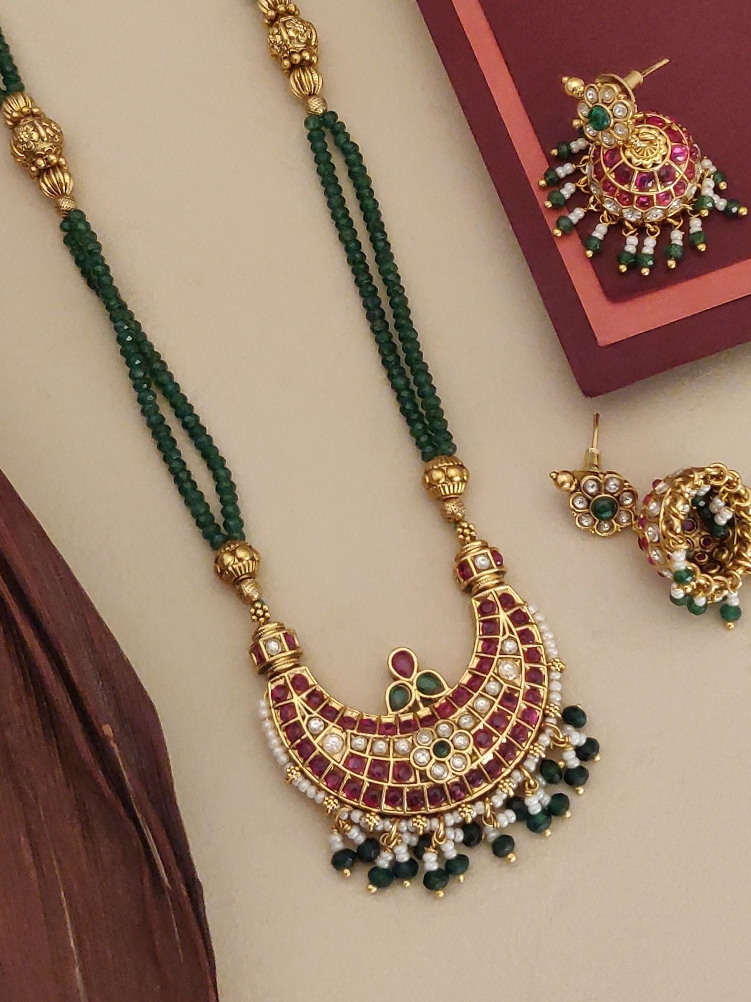 Gold plated long necklace with a green bead design and intricate red and white stone embellishments