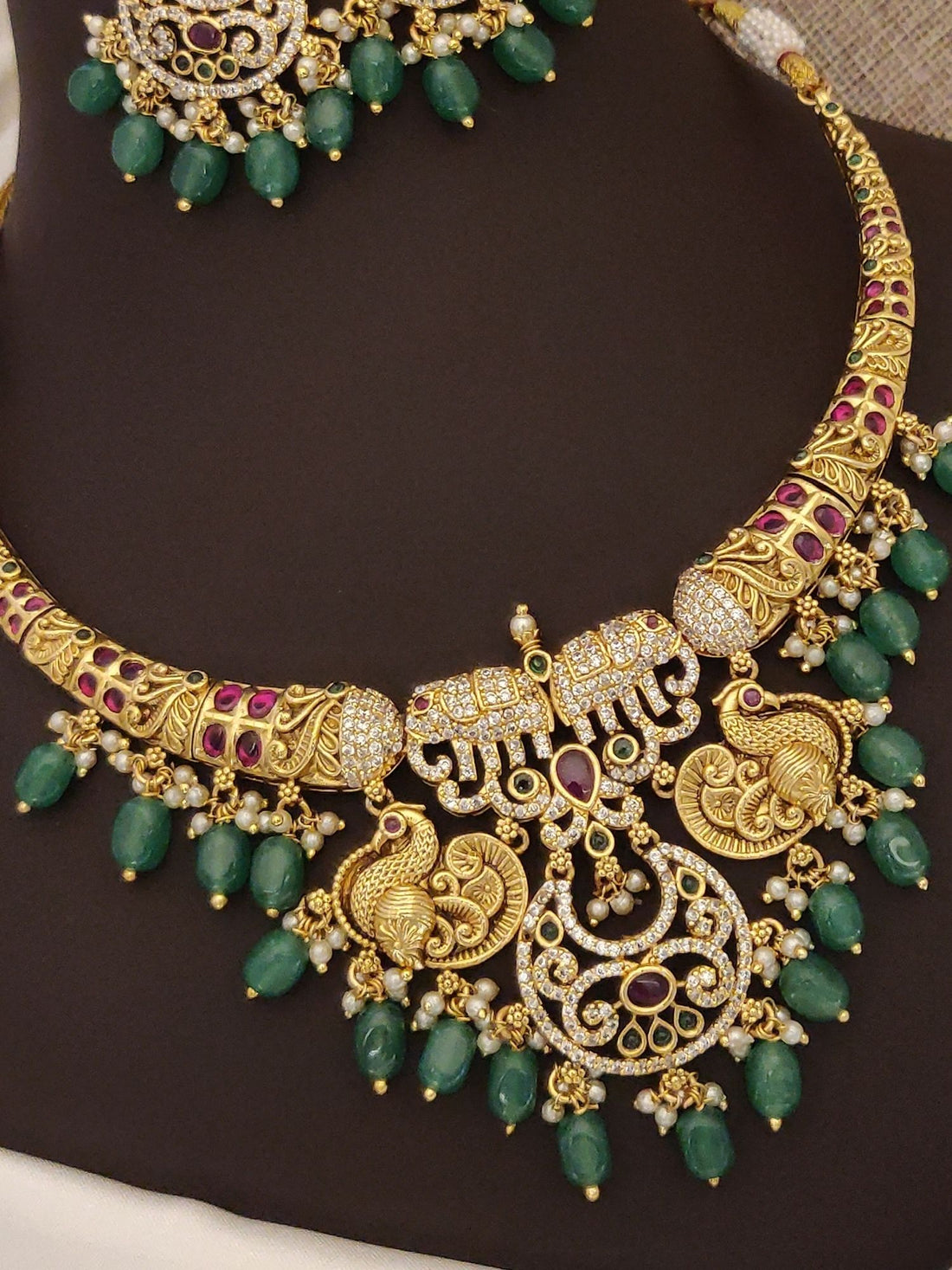 Gold plated multicolor diamond necklace set with intricate design and emerald accents