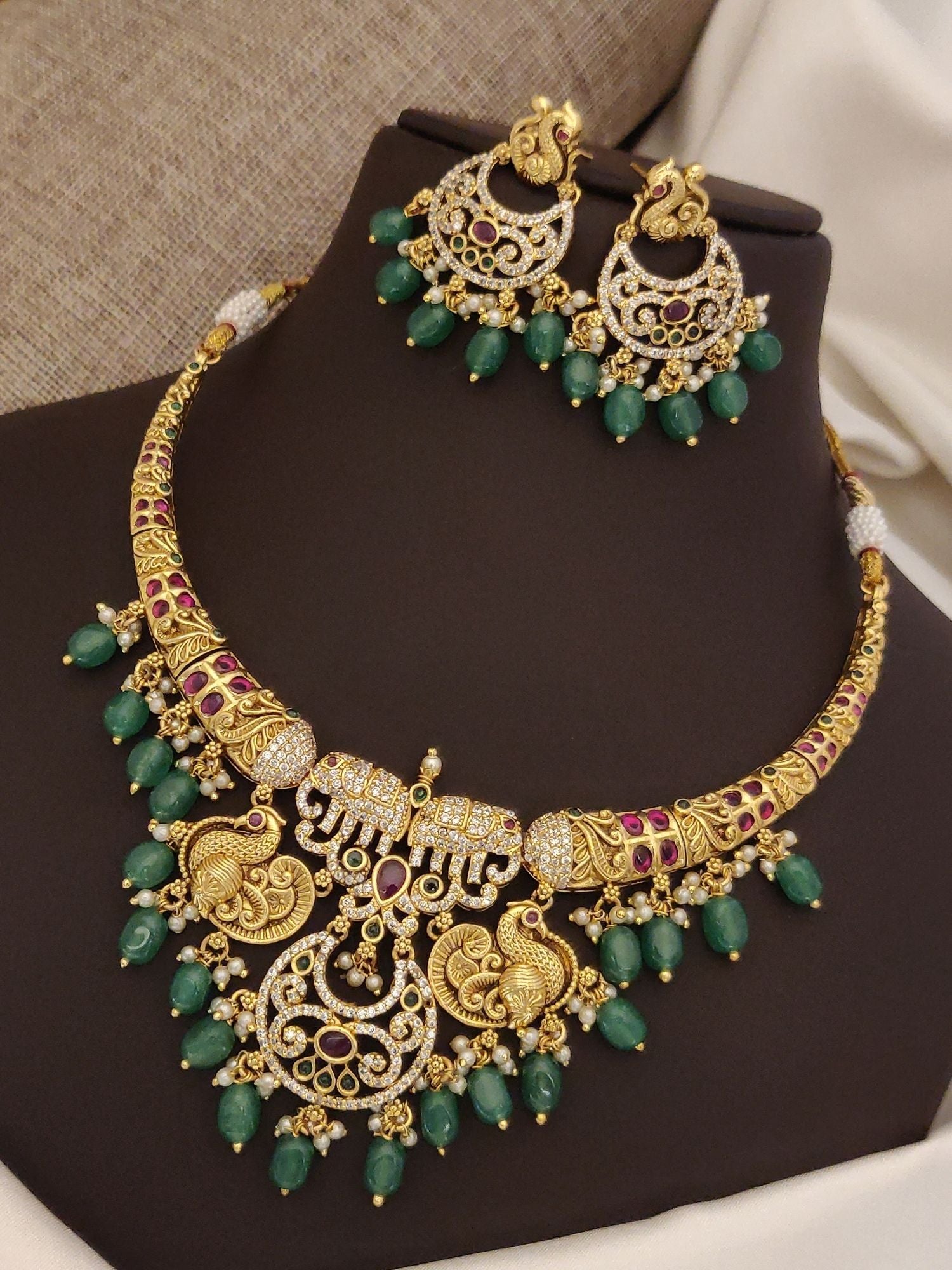 Gold plated multicolor diamond necklace set with intricate design and emerald accents