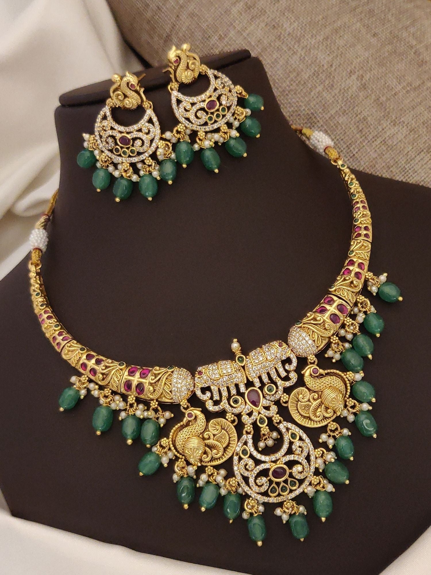 Gold plated multicolor diamond necklace set featuring intricate designs and green gemstone accents